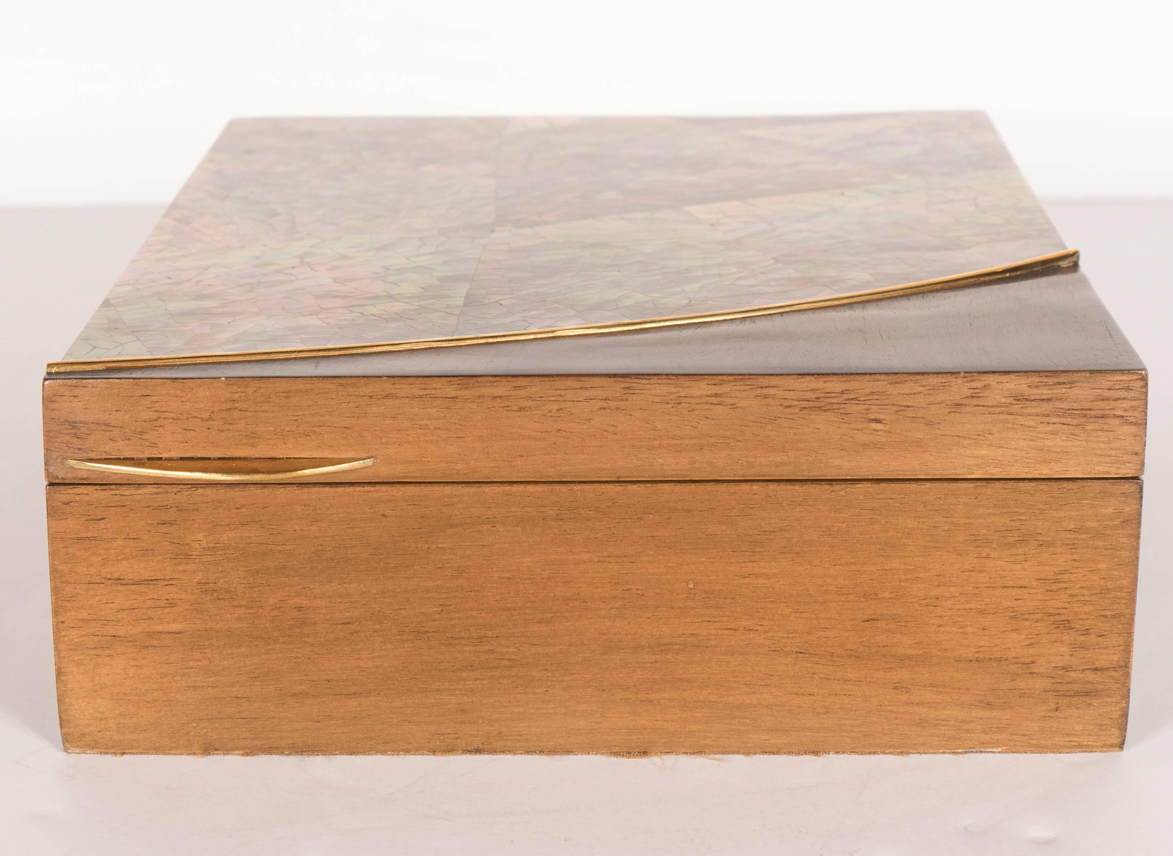 A truly stunning champagne-colored mother-of-pearl and hand-rubbed walnut box. A gorgeous mother of pearl shell top is bordered by a gold-plated inlay. A curved lid handle adorns the top. The interiors is lined with mocha suede. This piece is in