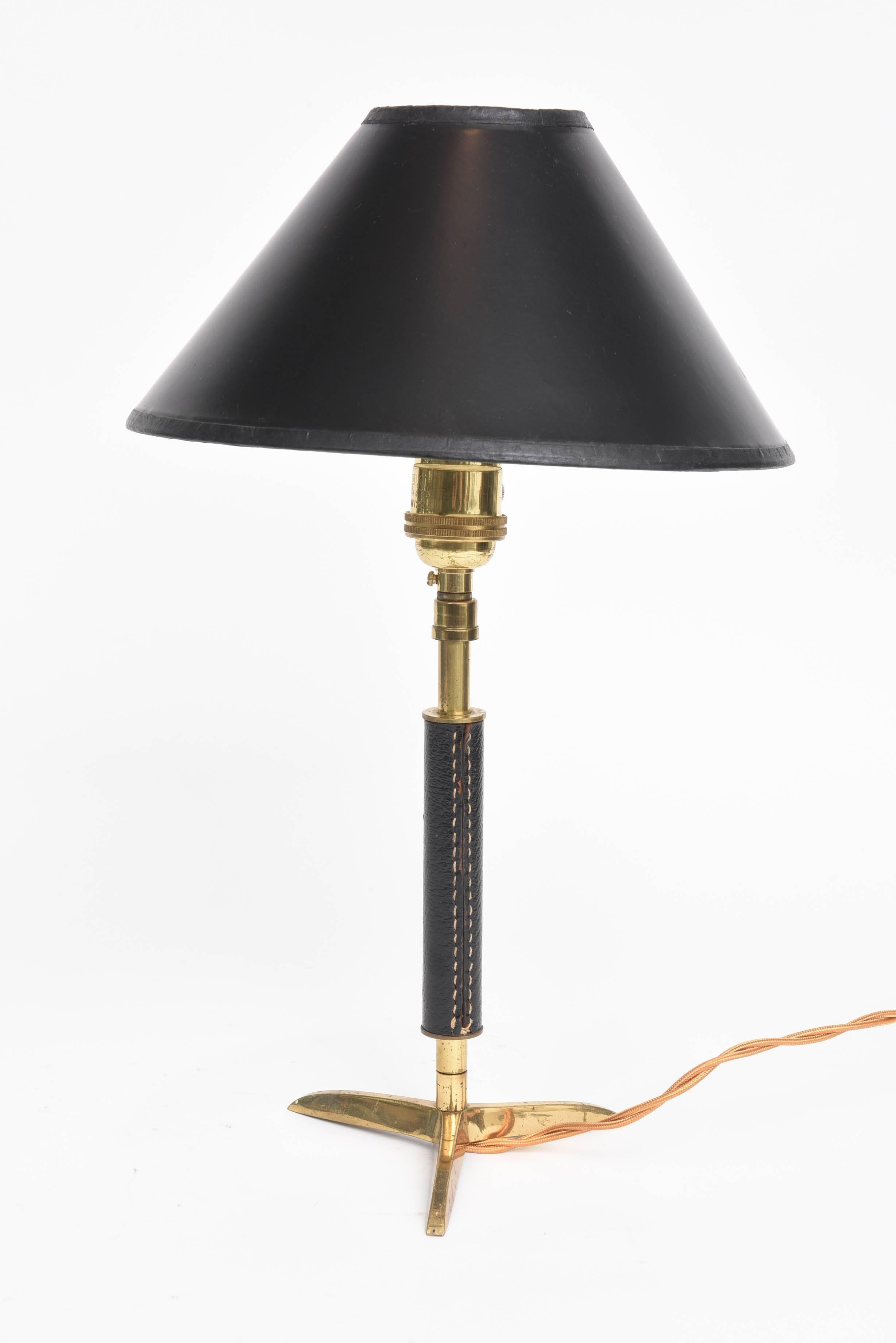 Handsome leather wrapped brass tripod lamp in the style of Jacques Adnet (1901-1984) a French Art Deco modernist designer, architect and interior designer.

Includes black paper clamp lampshade.