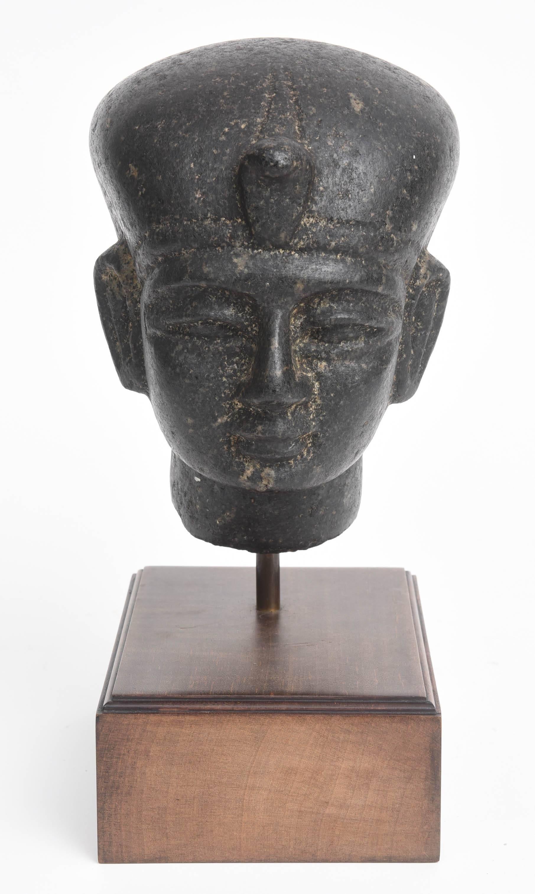 Exquisitely carved head of the pharaoh wearing a head cloth with fragmentary uraeus with a serene expression.  

Ex. collection Theodore and Aristea Halkedis
Acquired London 1980s