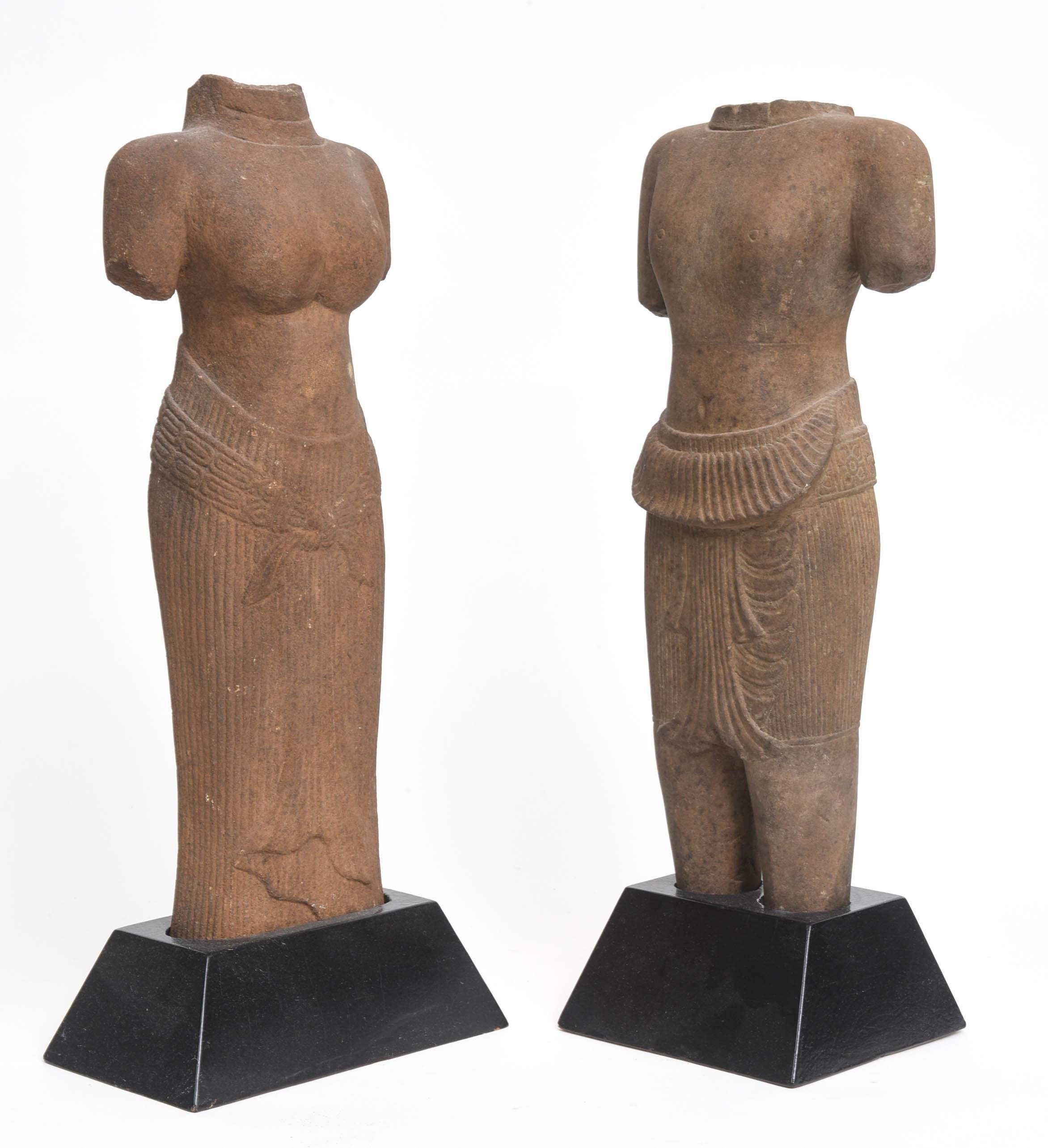 Finely carved 11th century, Baphuon Style,  Khmer, Angkor Wat period sandstone full-length torsos of two Hindu deities standing in typical postures, probably Uma Parvati and Vishnu.  He is wearing a vertically striated sampan held together with a