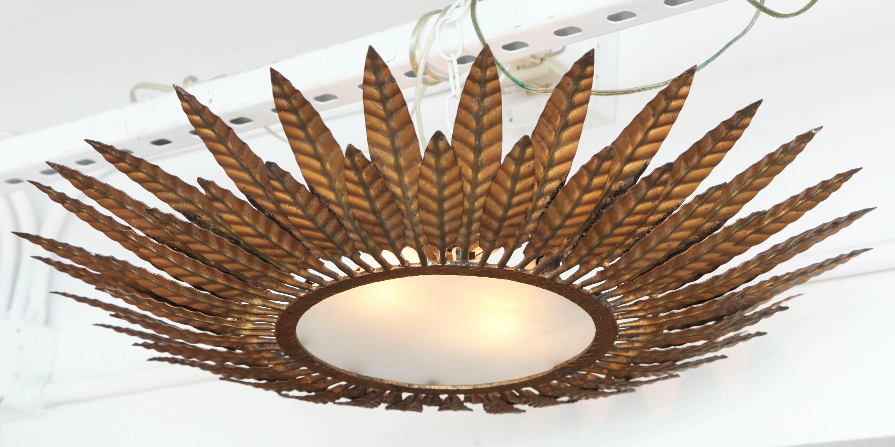 French bronze flush mount light fixture with central round frosted glass shade surrounded by alternating lengths of bronze leaves, circa 1940.