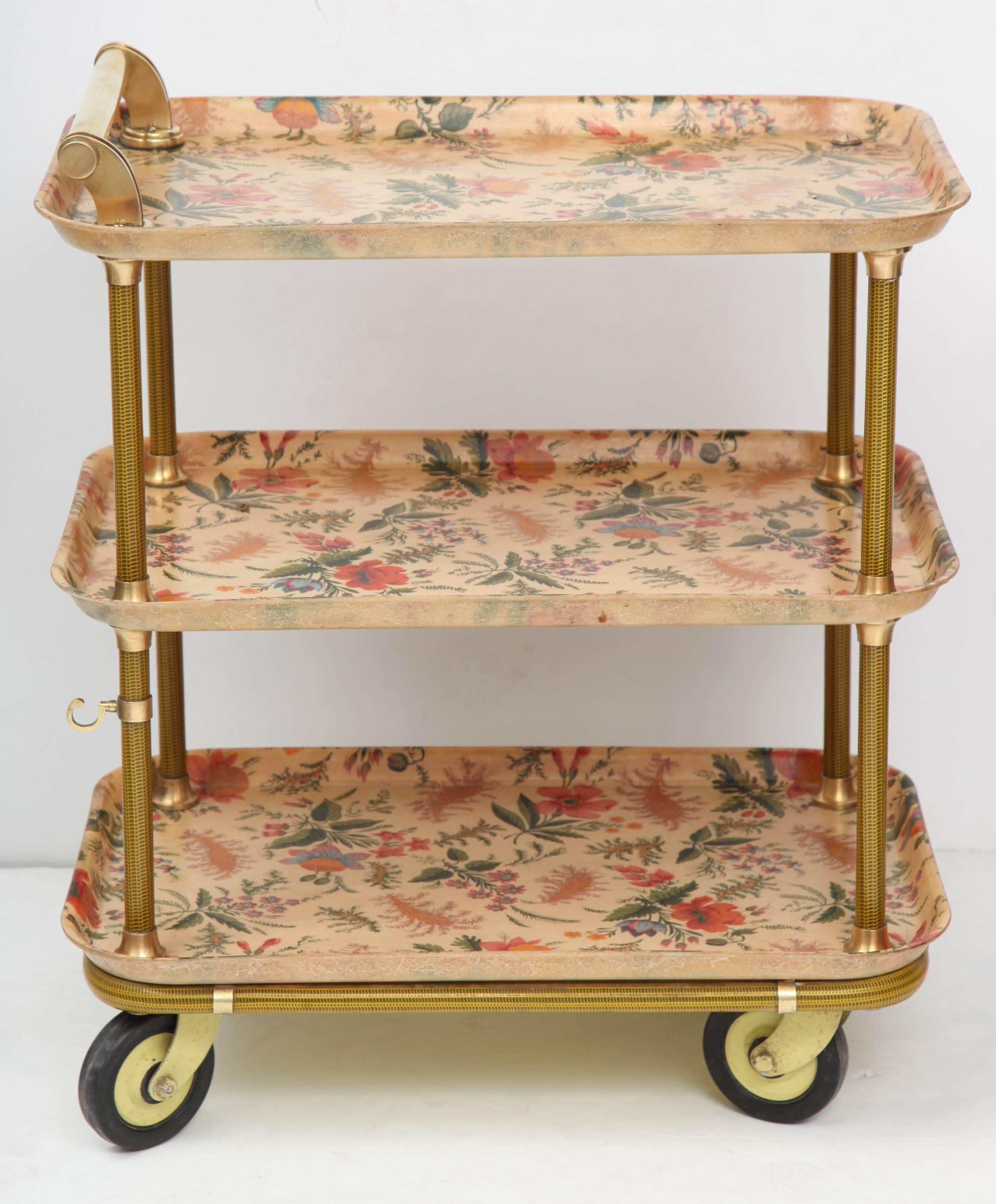 A three-tier serving cart with flowered fabric laminated into fiberglass trays, supported on a frame of woven gold-colored fiberglass rods with polished brass mounts, French, late 1950s. Top serving surface 25