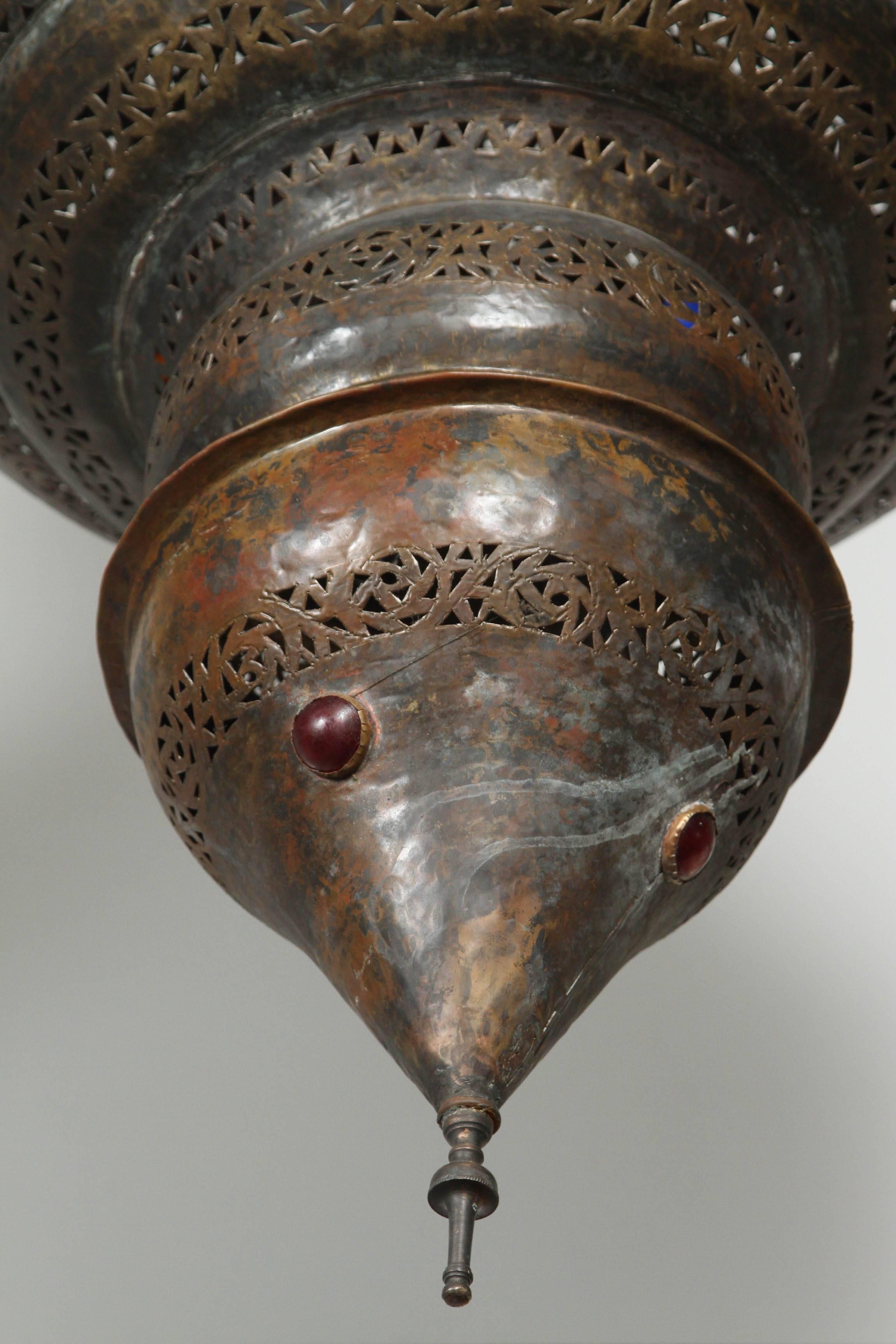 Grand lustre marocain en bronze patiné.
Ce grand lustre mauresque est délicatement sculpté et martelé à la main avec des motifs floraux mauresques, incrustés de petits bijoux en verre coloré.
Couleur bronze huilé antique.
Le luminaire a une hauteur