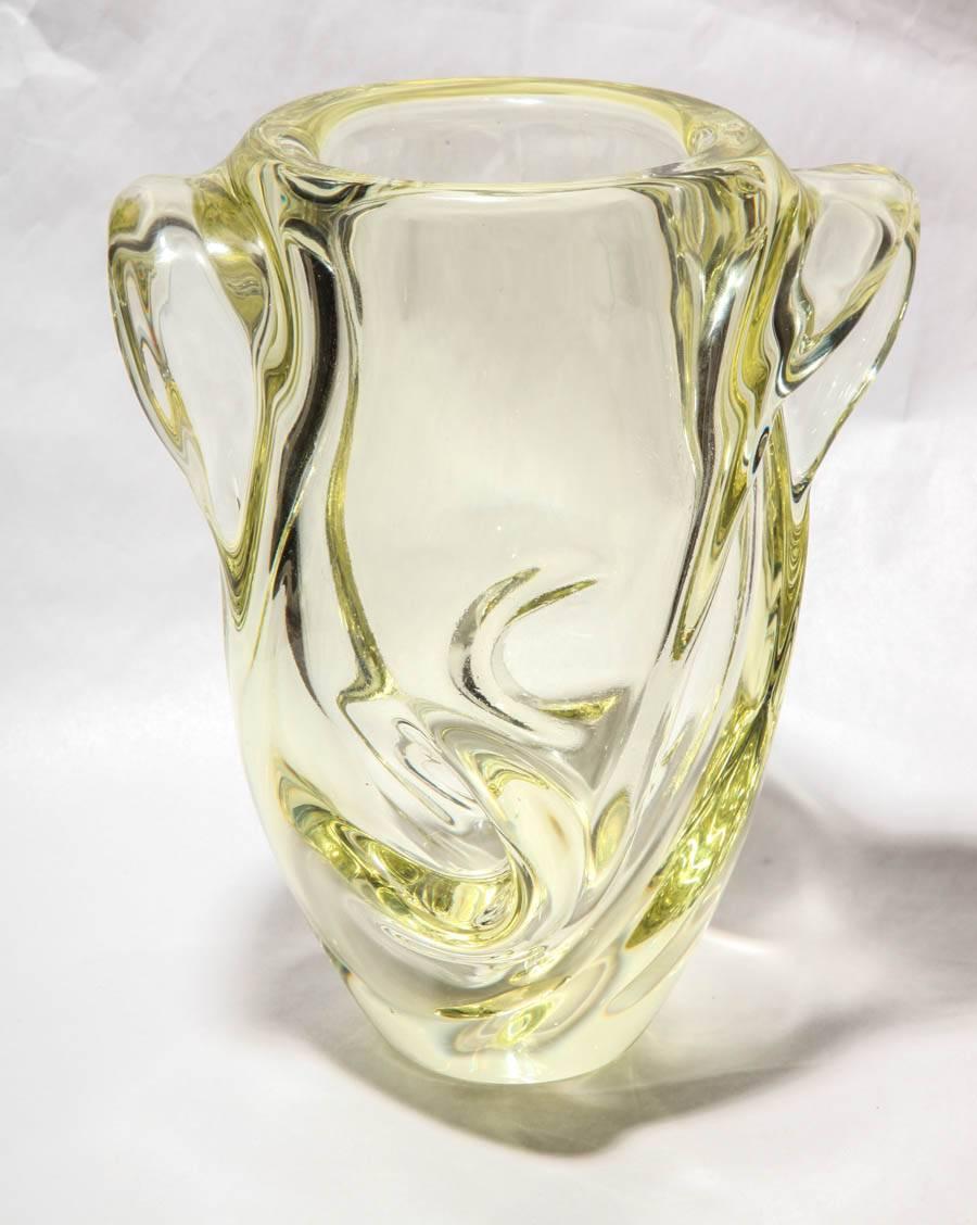 A good and heavy weight French glass vase of a pale yellow color, featuring a fluid molded movement to the handles and body. The base underside bearing a mark of Sevres, France.