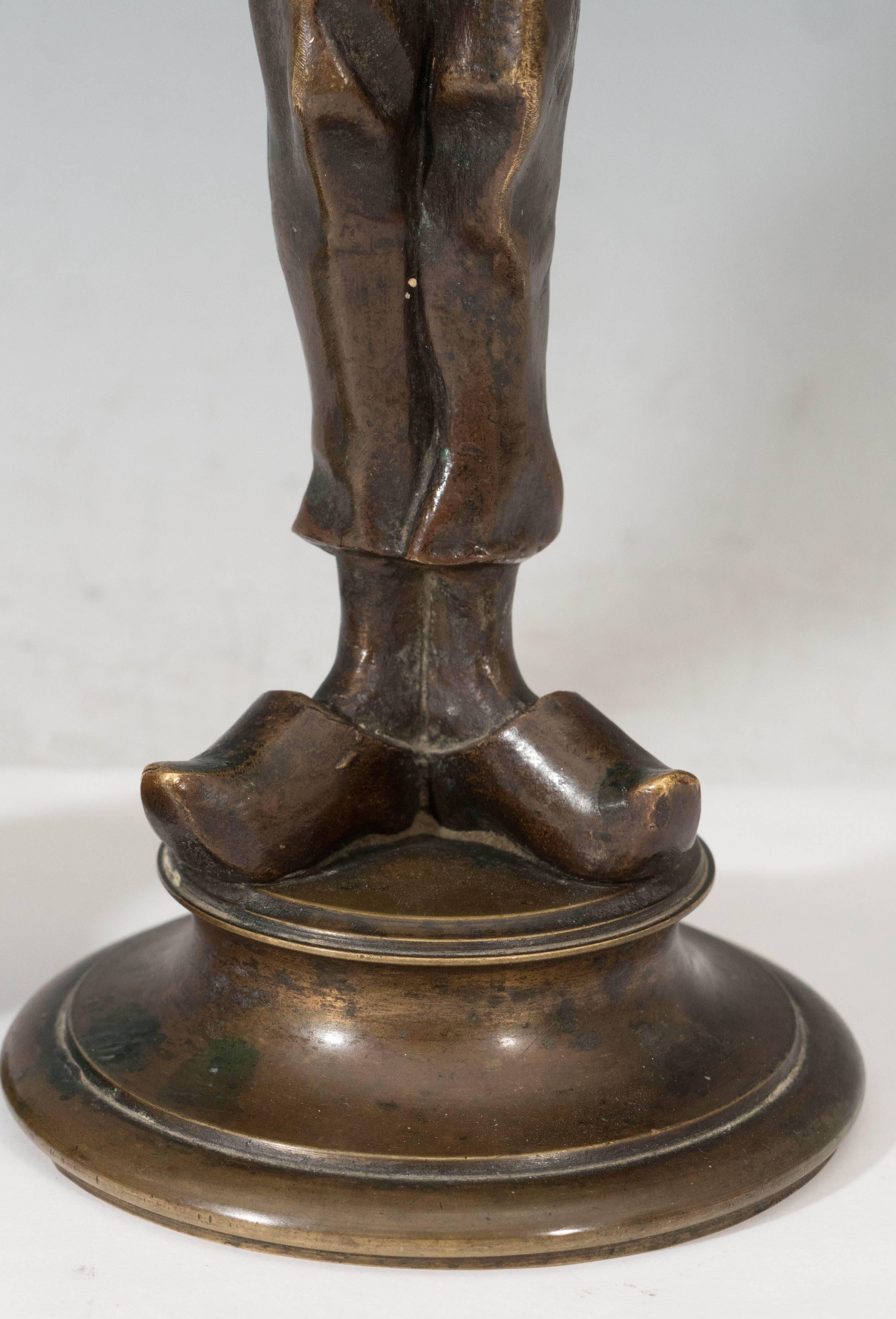 This unusual pair of bronze candlestick holders come designed as two comical soldiers, a gangly young man paired with a higher ranking older man with a long twisted beard. Each piece is in very good condition, with age appropriate patina to bronze.