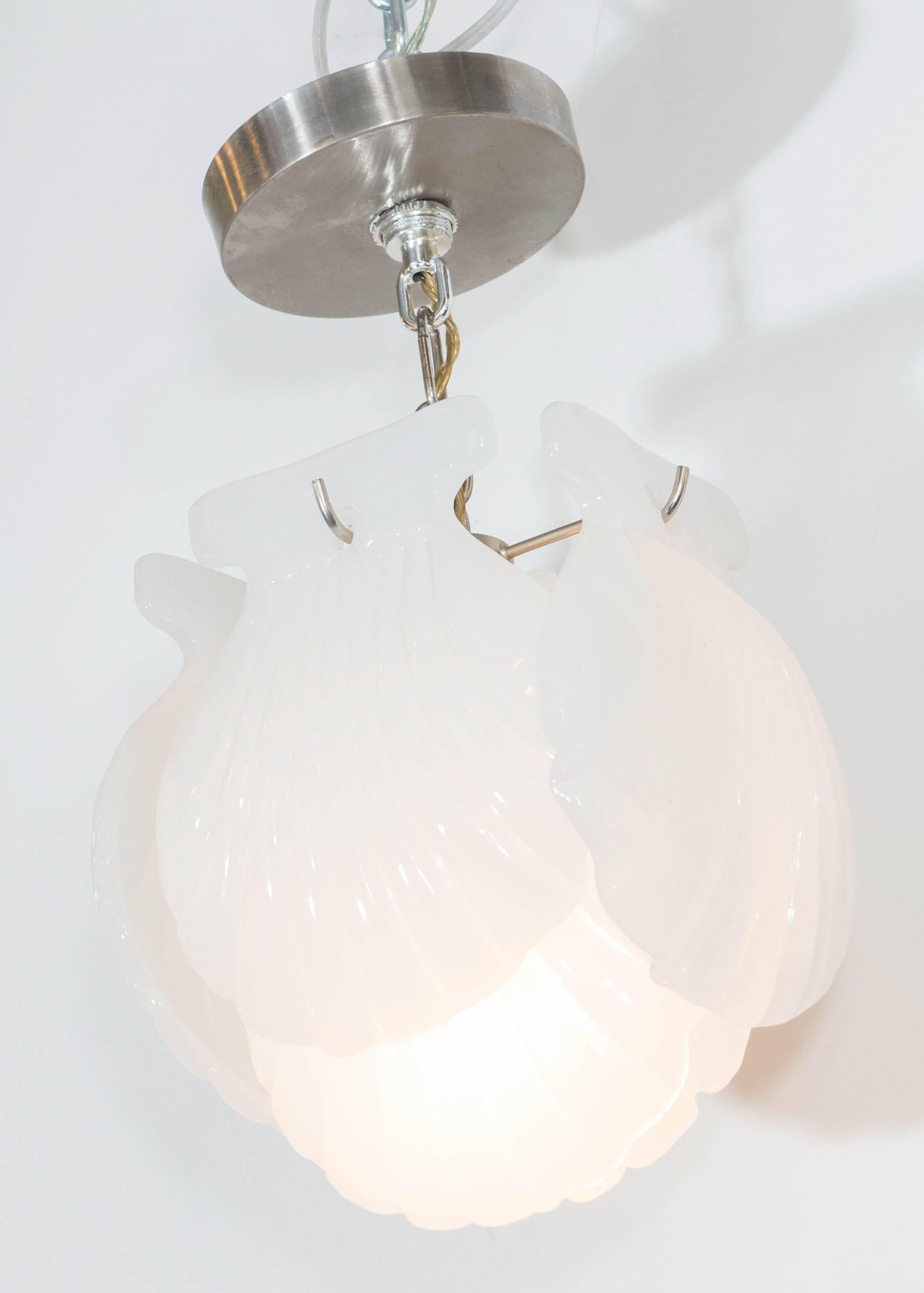 An Italian pendant light, with six white opalescent scallop shells in Murano glass, produced circa 1960s, each suspended in layers from a metal frame and circular canopy. Wiring and socket to US standard, requires a single Edison base bulb. This