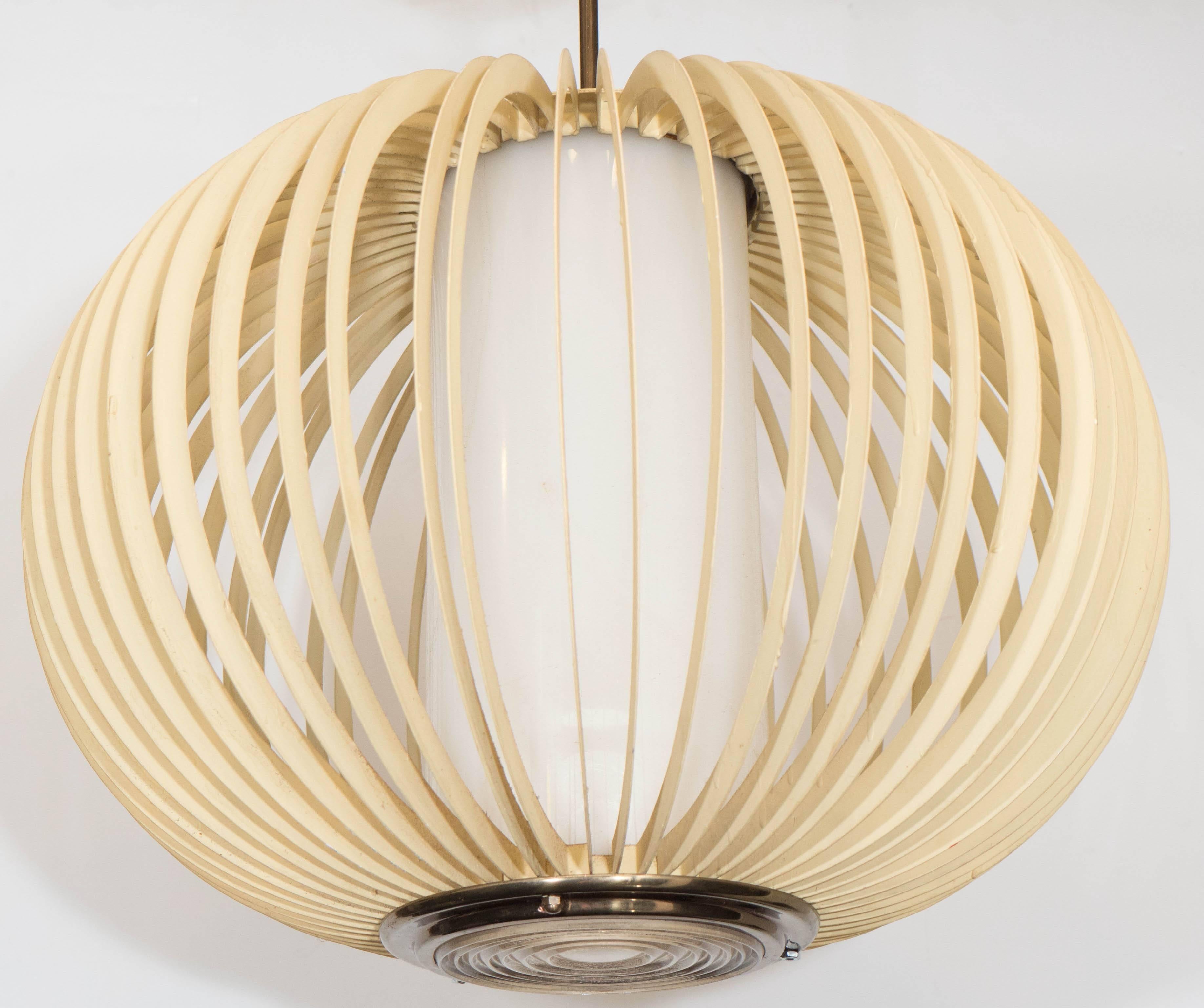 A vintage, hanging light pendant, produced circa 1970s, with cylindrical milk glass shade, caged within surrounding curved metal panels, coated in soft toned yellow paint, entirely suspended from brass domed canopy; borosilicate glass diffuser