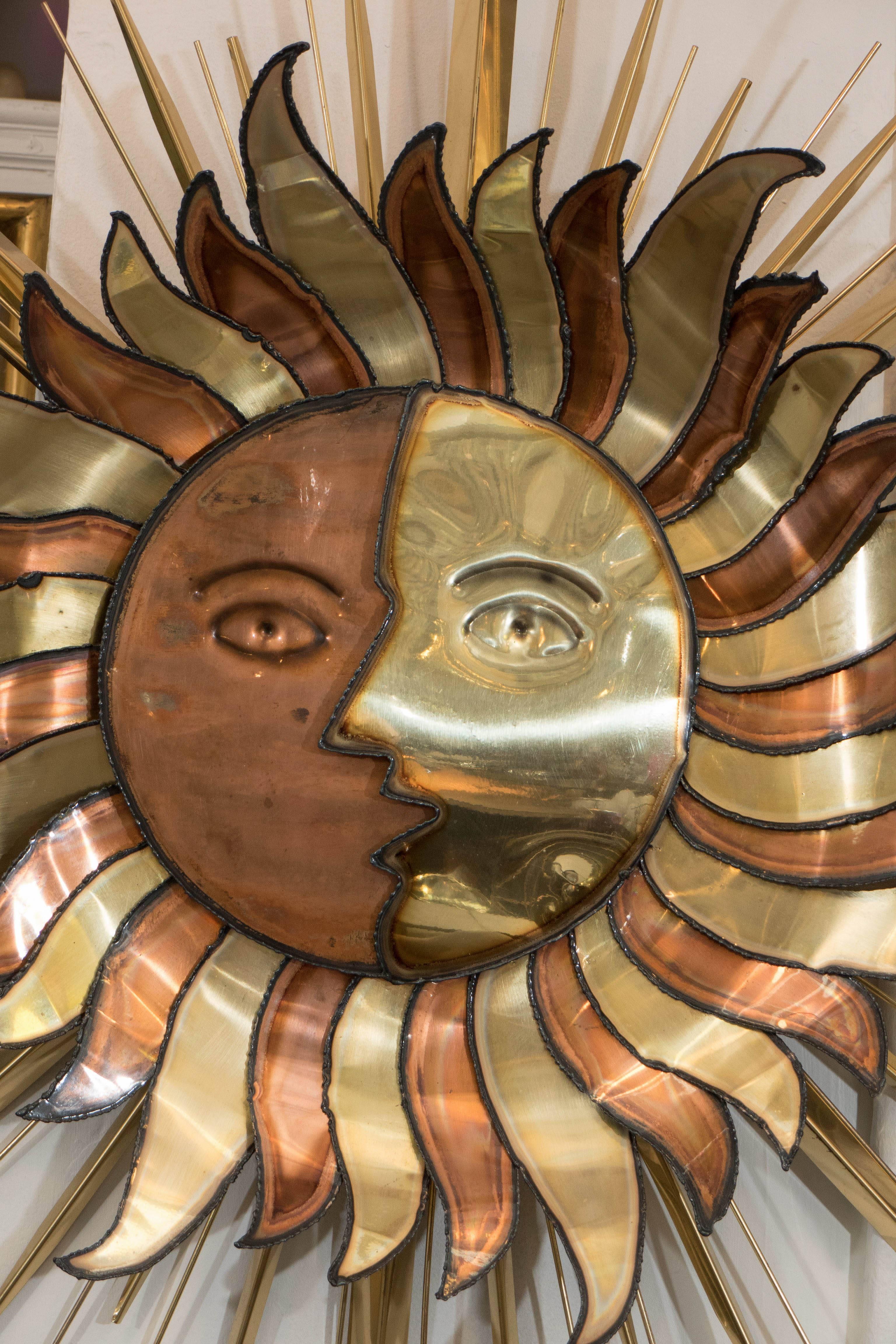 This Brutalist style wall sculpture depicts a personified sun and moon, combined as one celestial body, in beautifully contrasting sheets of mixed metal, torch-cut, soldered and enameled, in tones of copper and brass, surrounded by lengthy spires