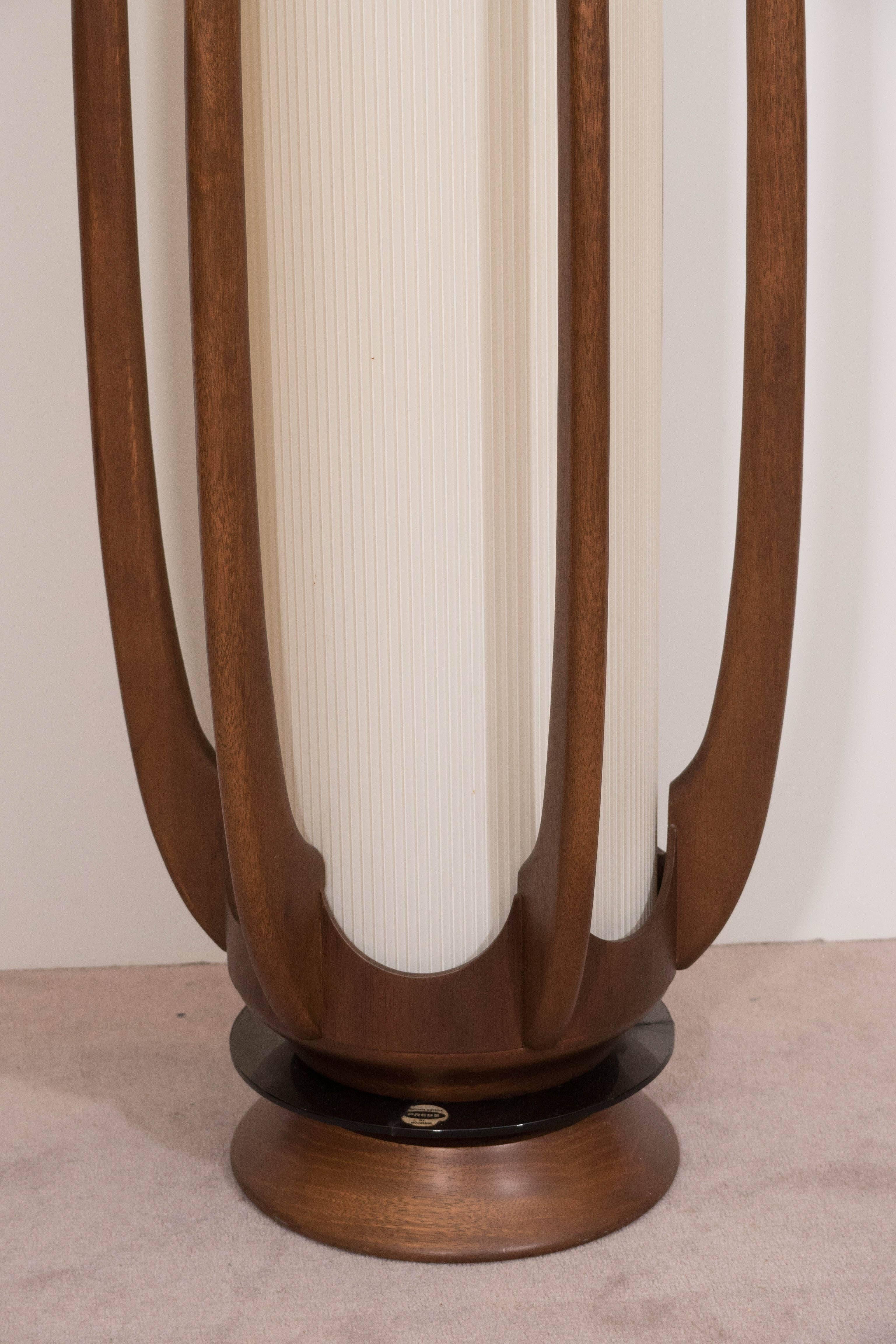 A vintage sculptural floor lamp, produced by Modeline, circa 1950s-1960s, designed in the Scandinavian Modern style, with a lengthy, pleated linen cylindrical shade, affixed to a wooden frame, consisting of six, gently curved brackets as support,