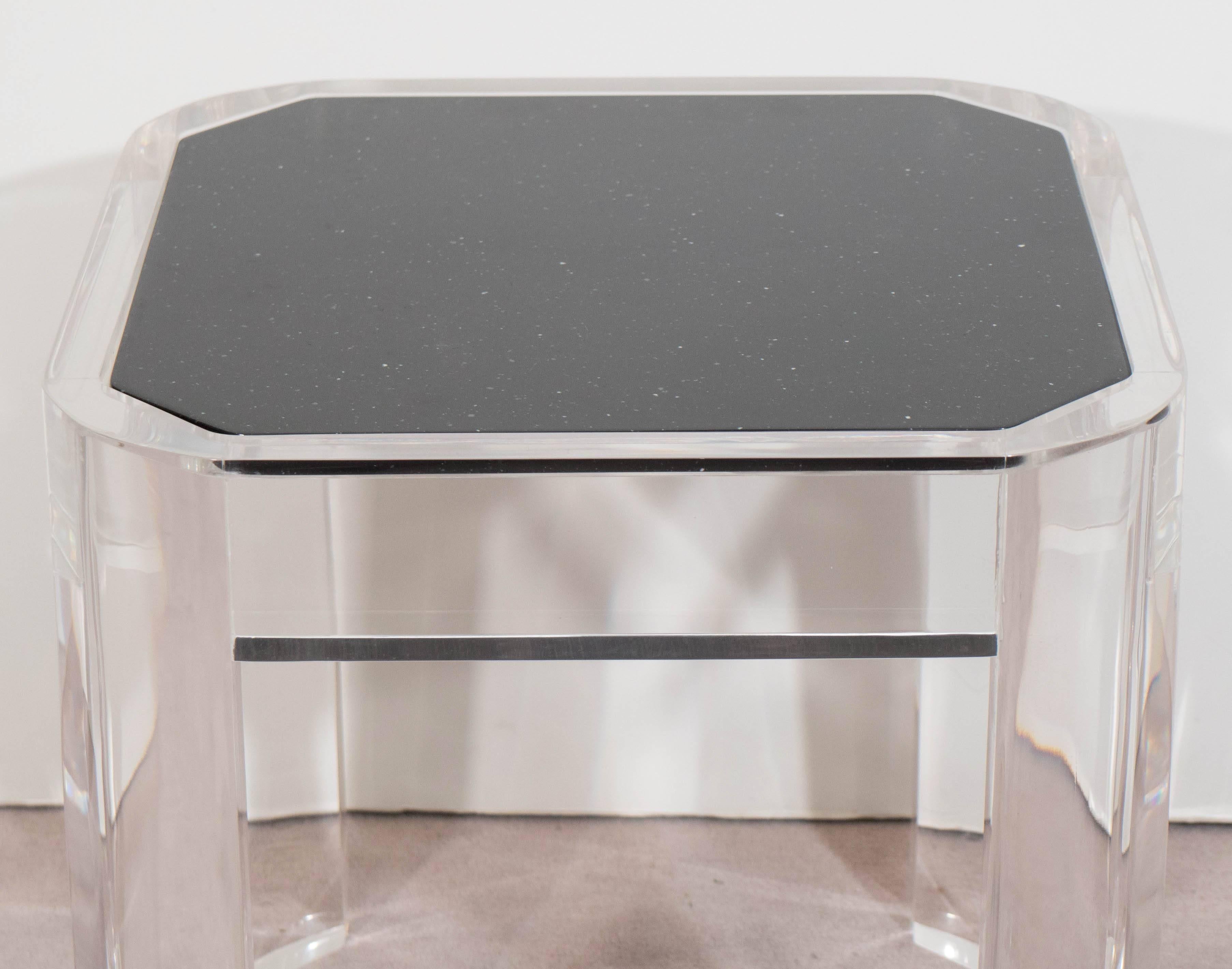A highly modernistic side table, designed in the manner of Karl Springer, with beveled black faux granite top, inset within a very clear Lucite frame, with smooth, rounded corners. Other than some minor scratches to the surface, this piece is in