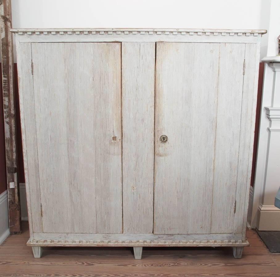 Painted Gustavian two-door sideboard with two interior shelves; reeded doors and feet.