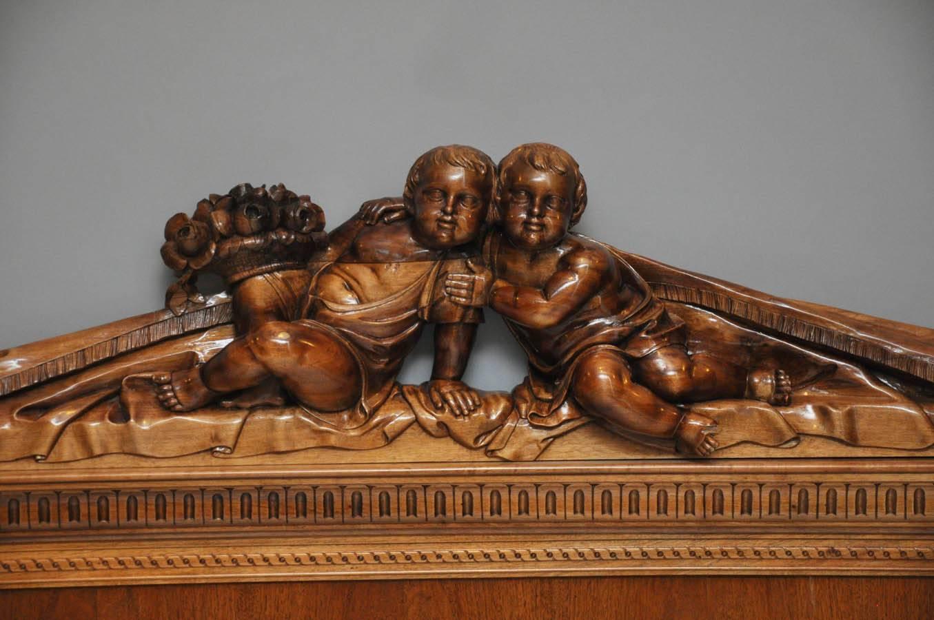 19th century Venetian walnut bed. Renaissance inspired pair of cherubs draped in fabric with urn of flowers surmounting the headboard. Footboard with a crouching putti on each end holding up loosely draped fabric.