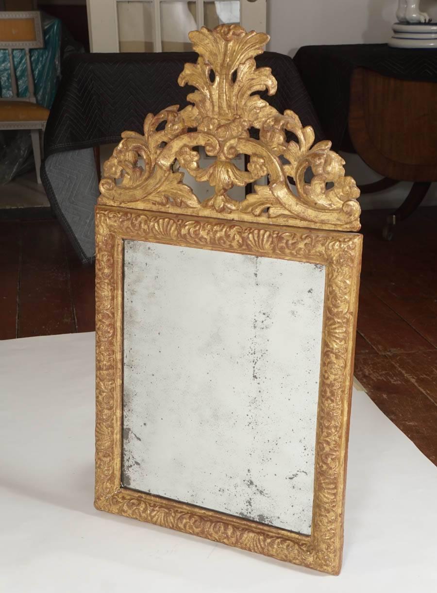 Exquisite Danish Baroque, circa 1700, mirror or looking glass having carved giltwood frame with dramatic foliate cresting and rectangular cushion-frame with foliate and seashell motif; rare original bevelled mirror plate with attractive patination.