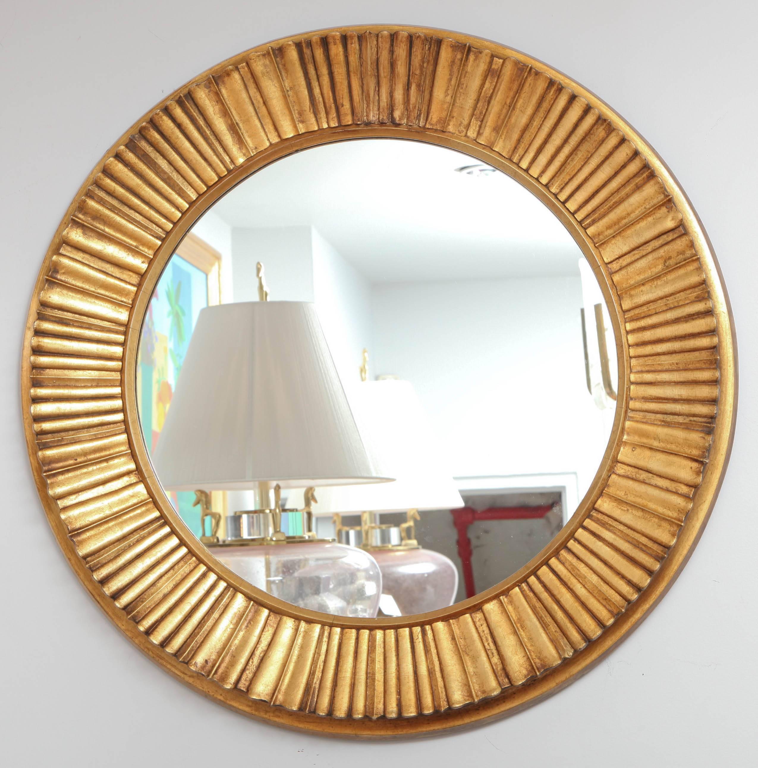 A stylish large circular mirror of carved gilt gold wood.
