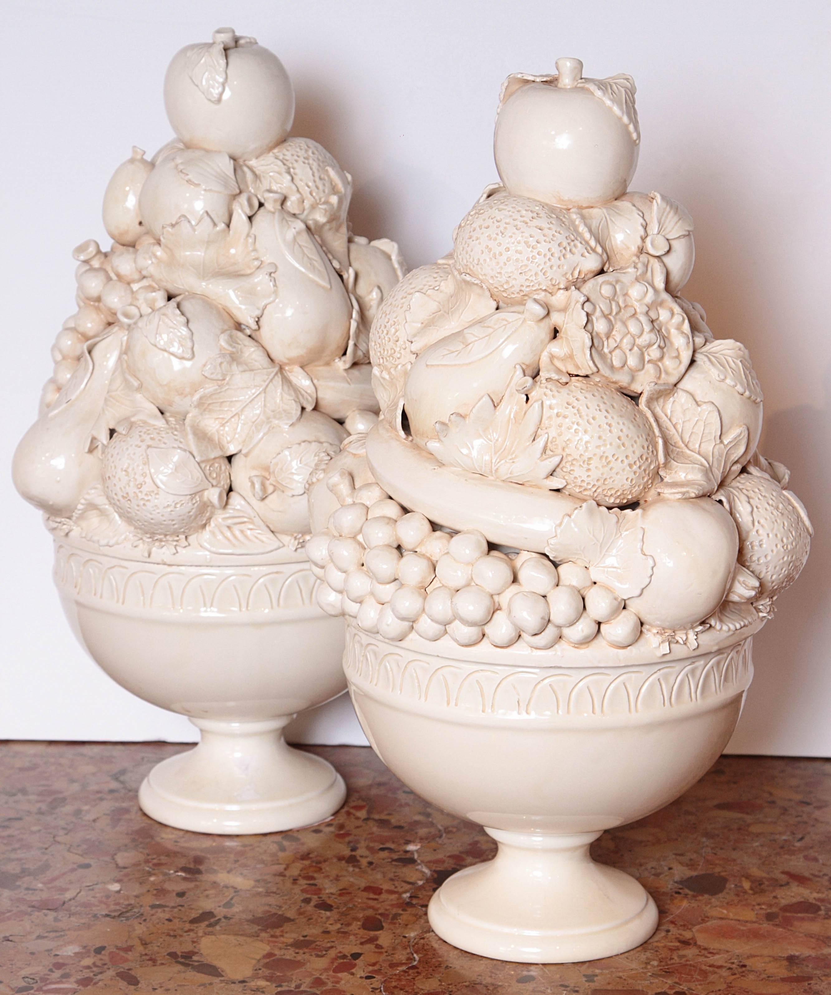 These Italian creamware pedestal bowls of fruit have been very realistically done. There are grapes, open pomegranates, bananas, oranges, apples and pears, with their leaves peeking through and curled over the fruit. The bowls’ rims have linear
