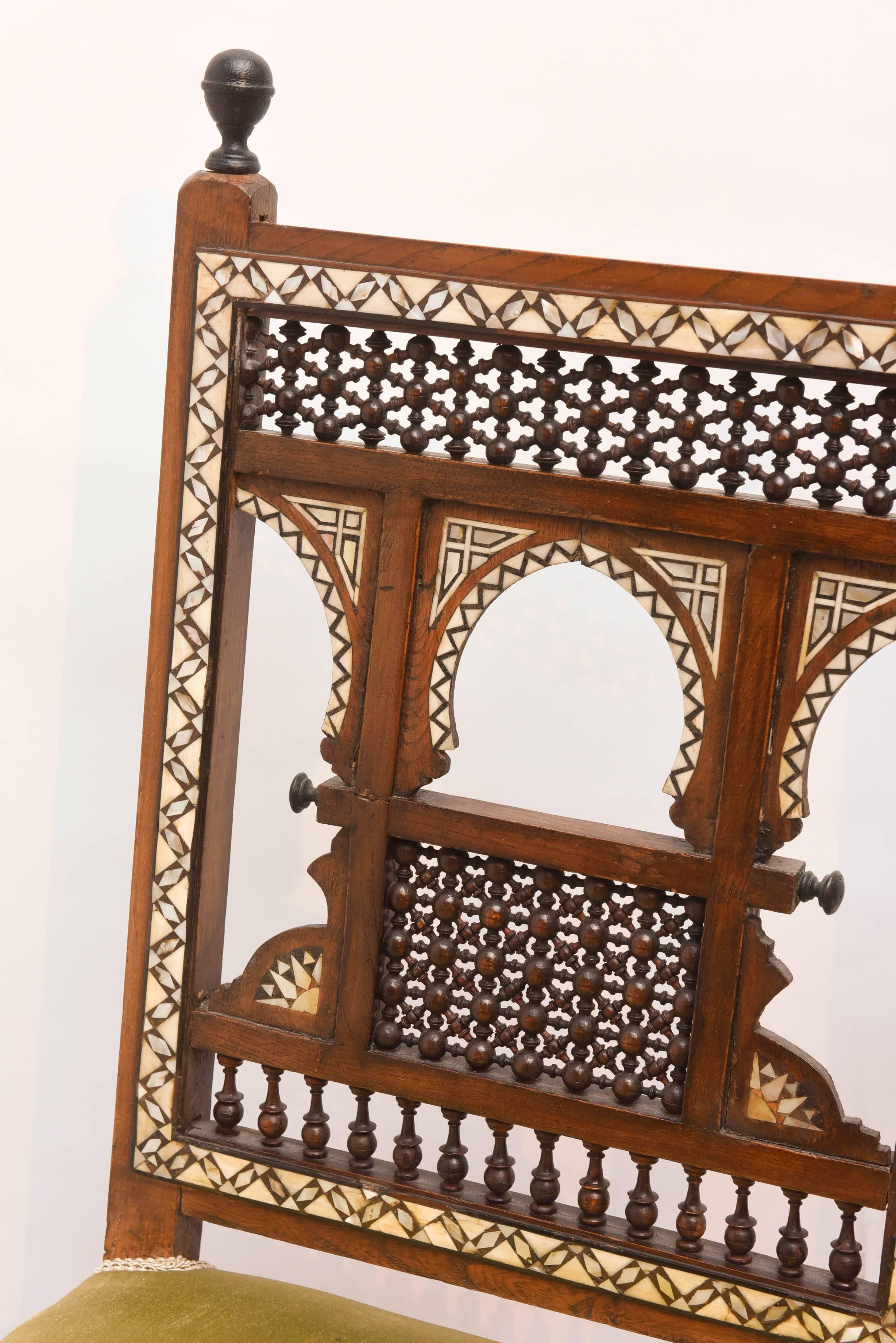 The pair of chairs is elaborately inlaid with exotic wood, mother of pearl and camel bone. The spindle-like adornment is intact and extensive.