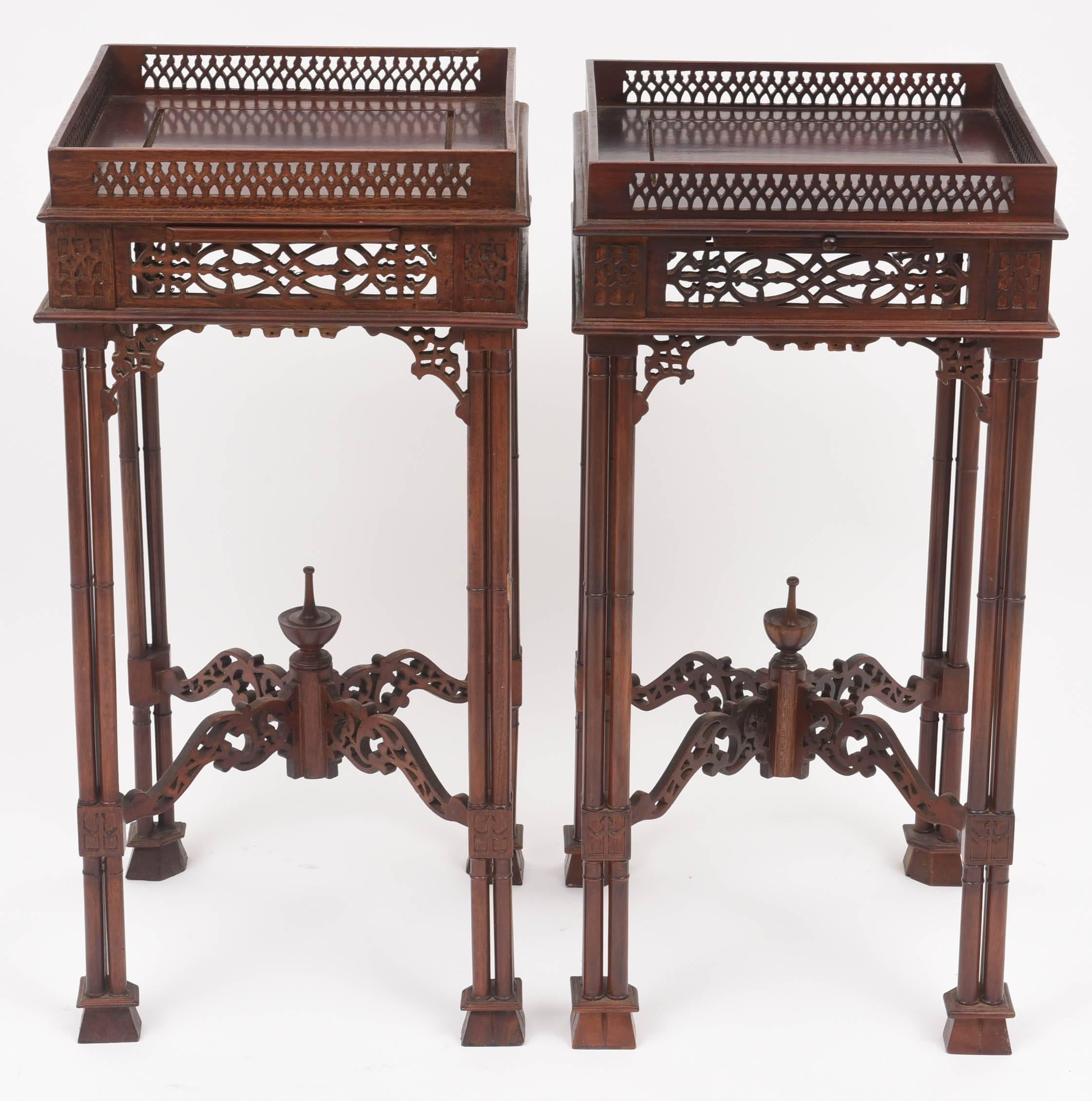 This handsome pair of mahogany side tables are in the style of Thomas Chippendale and his Gothic-revival period. With it's cloistered legs and fret-work gallery and apron. 

Note: One of the pull-out trays has a knob and the other does not