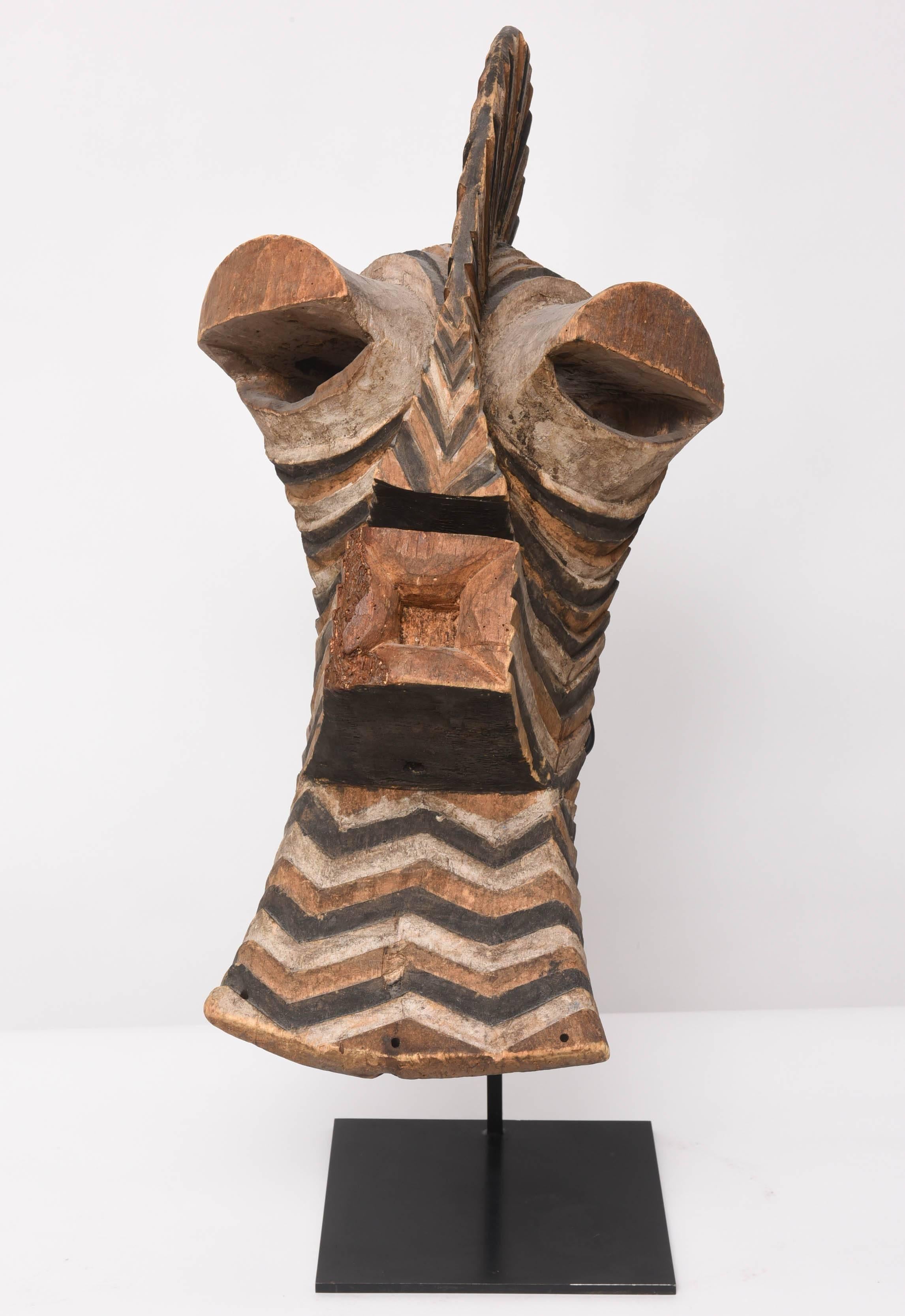 This 19th century large carved wooden mask with a chevron-pattern colored in ochre, white and black pigments, in the style of a ceremonial Kifwebe, of the Songye People, a Bantu ethnic group from the central Democratic Republic of Congo. Similar to