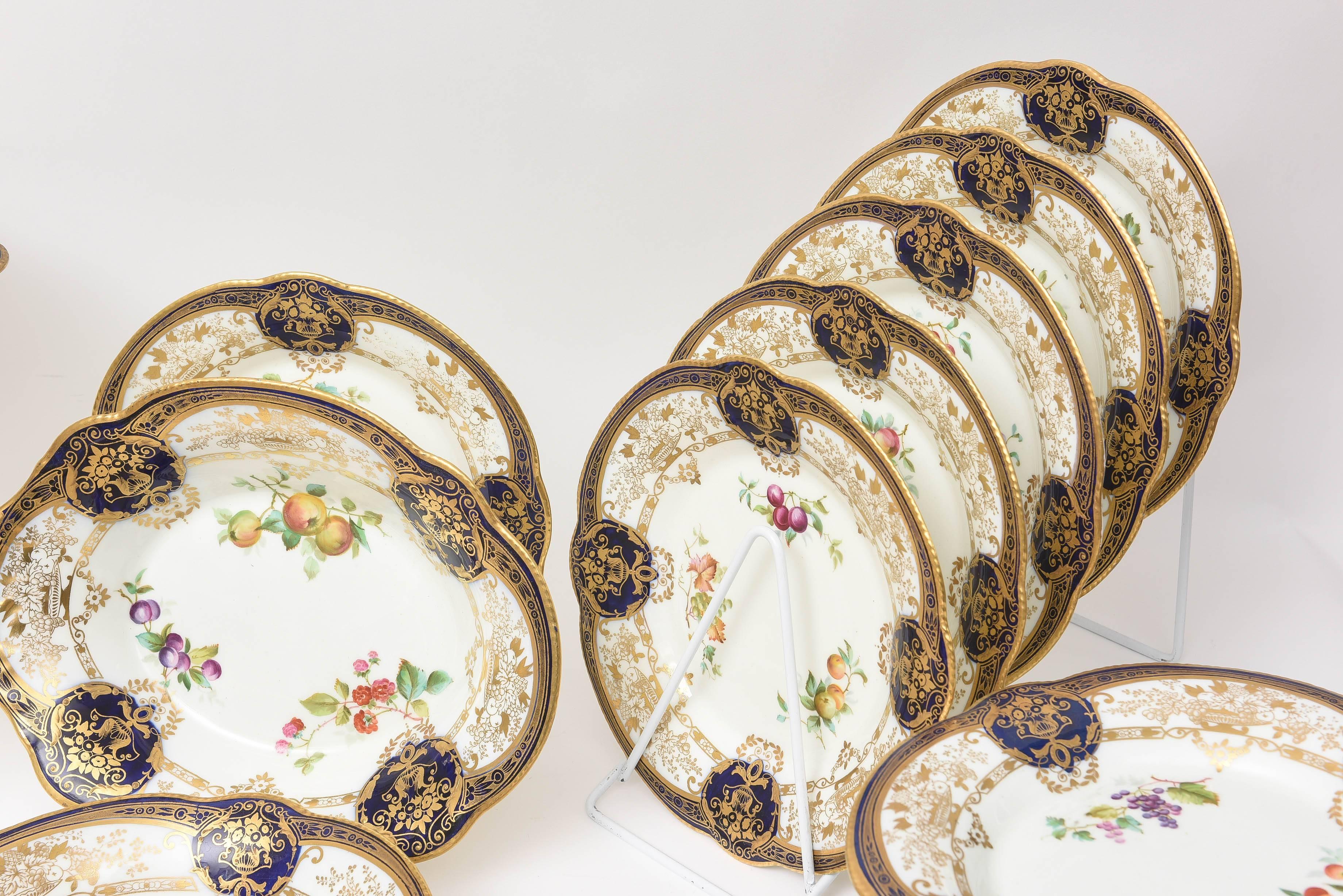 An elaborate and wonderful dessert service by a storied English porcelain firm: Adderly. Rich cobalt blue edges and cartouches, hand decorated 24-karat gilt throughout and hand-painted florals and fruits make this service especially beautiful.