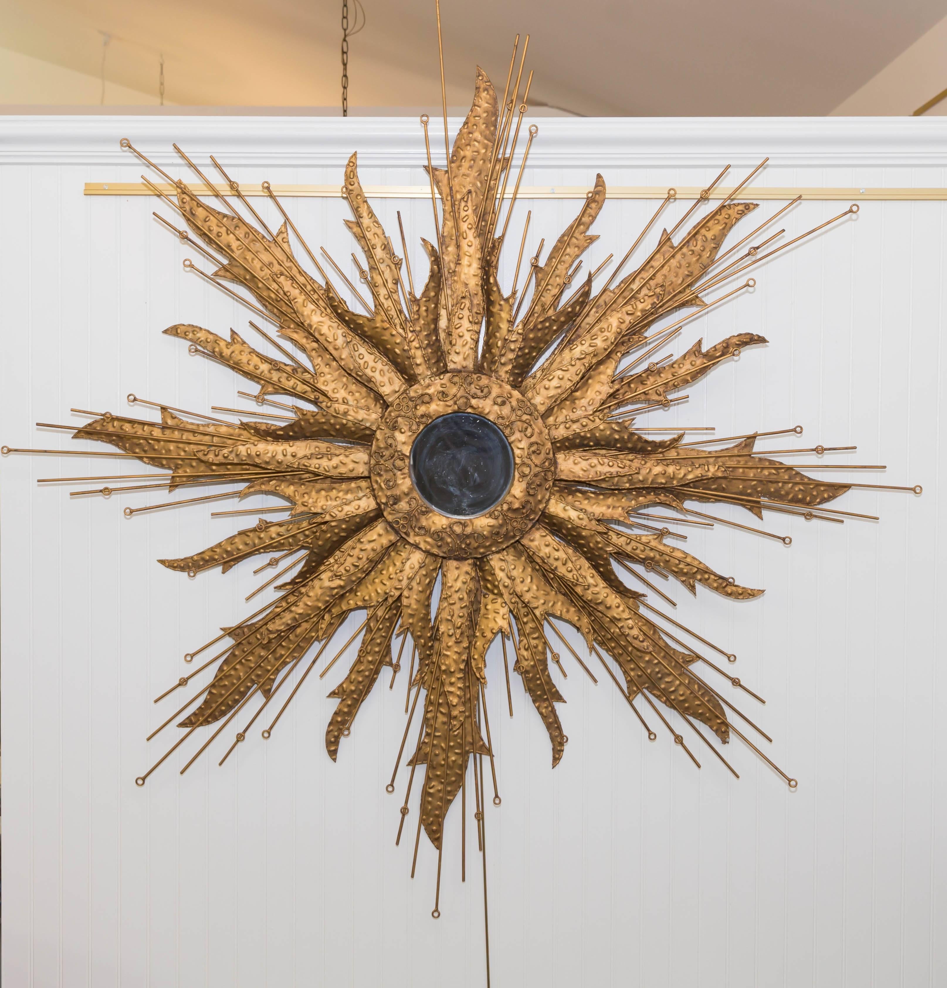 Metal sunburst shape mirror in the Brutalist style, radiating strips of metal forming sunrays with texture and iron rods interspersed throughout.