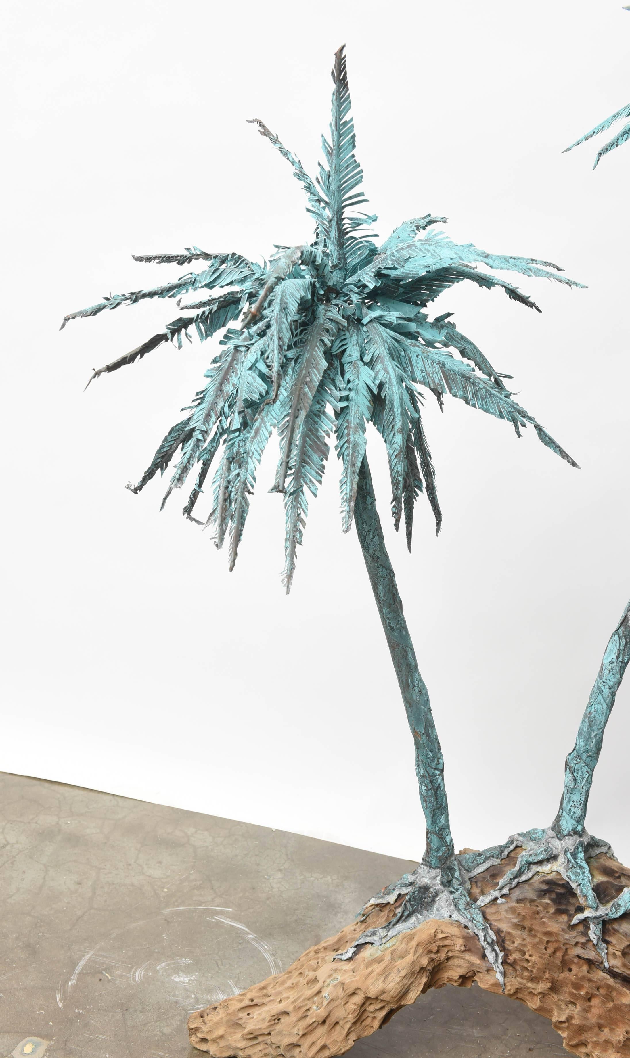 Wonderful and whimsical patinated metal palm trees on driftwood base, in Brutalist style. Piece is large and dramatic at just over 4 feet tall and 38