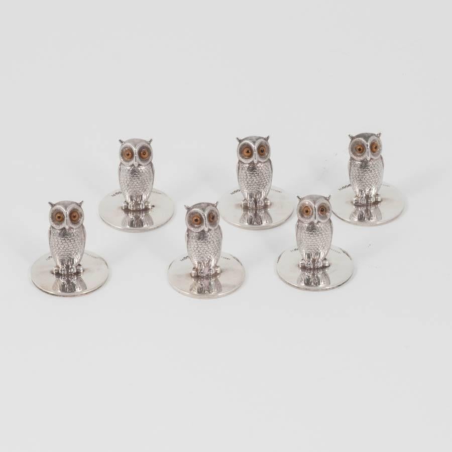 This charming set of six sterling silver menu holders or place card holders, modeled in the form of owls, are in their original presentation box from R. Stewart, a retailer from Glasgow. Each owl has its original glass eyes bears the hallmarks for