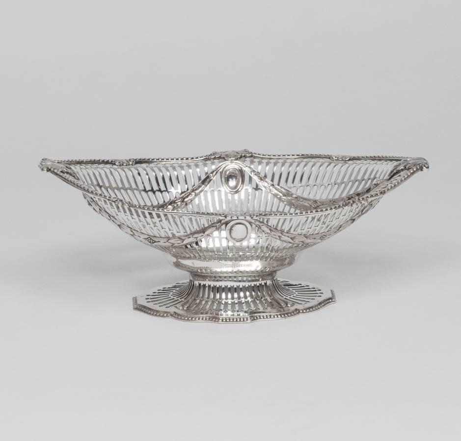An elegant pair of Victorian sterling silver fruit baskets with finely hand-pierced decoration and cast bead, scroll and leaf mounts on the border. This pretty pair of dishes, in the neoclassical style, would make ideal bread baskets or could be