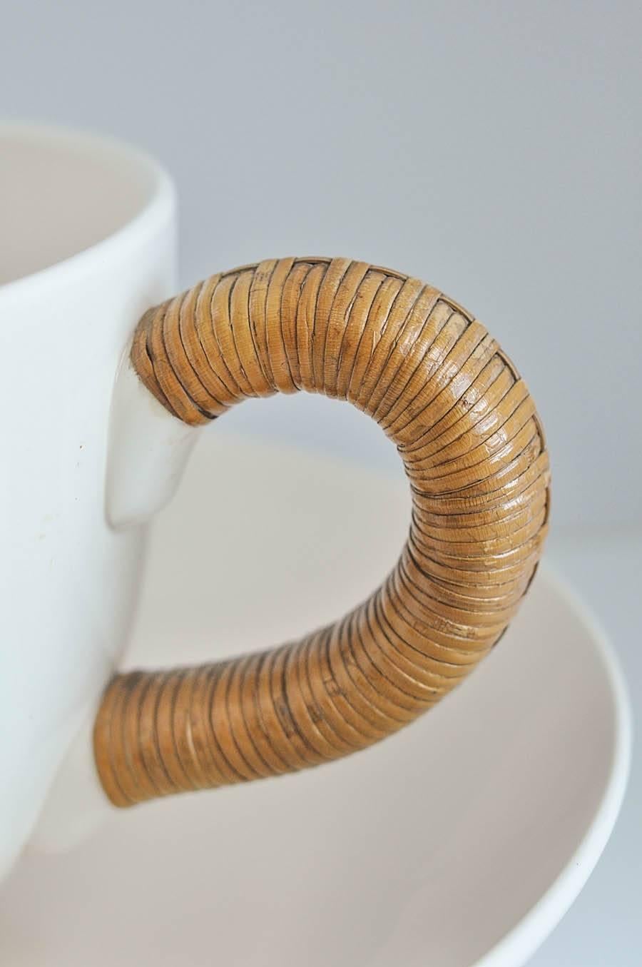 A large-scale replica of a cup and saucer with a wrapped rattan handle by the American Industrial designer Ed Langbein. By altering the scale of an everyday object and elevating it to sculpture, Langbein seems to signal the beginnings of the Op Art