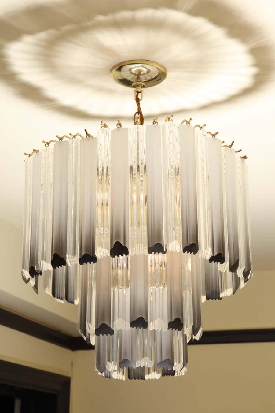 With clear and smoked lucite pendants arranged in three graduating tiers.