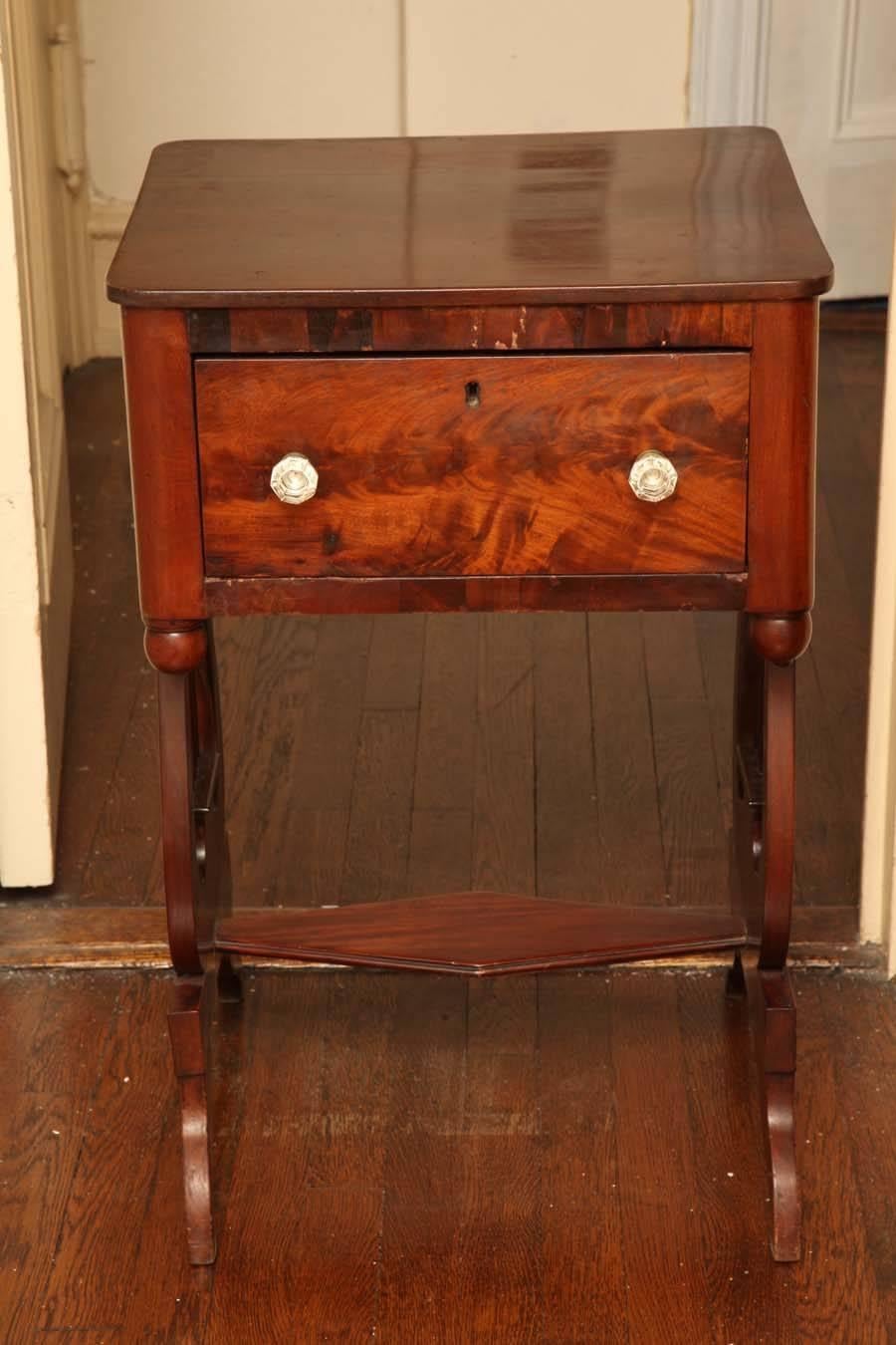 The rectangular top with rounded corners over a deep frieze drawer with lively flame figure and cut-glass knobs, raised on lyre-form end supports on downward swept feet.