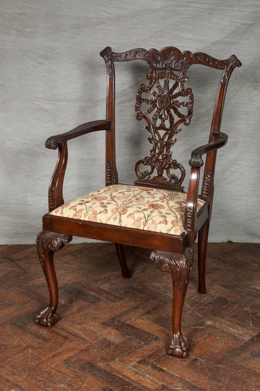 A very good quality set of 12 Chippendale influenced dining chairs (two arms, ten single). The backs having carved ribbon back decoration, drop in upholstered seats and raised on carved cabriole legs, terminating in ball and claw feet.