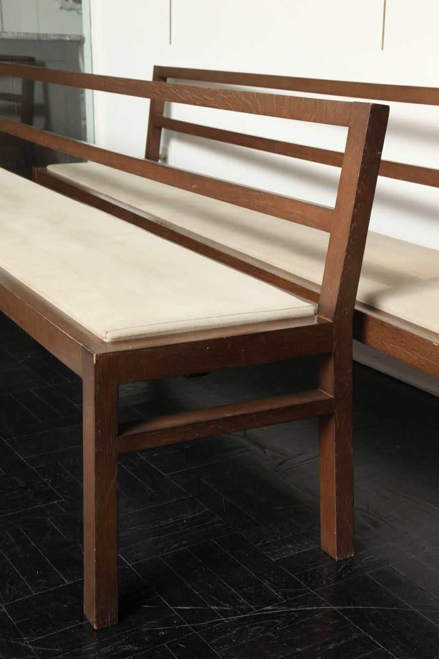 Pair of 20th century stained oak long benches, open-back, upholstered seats, straight square legs.