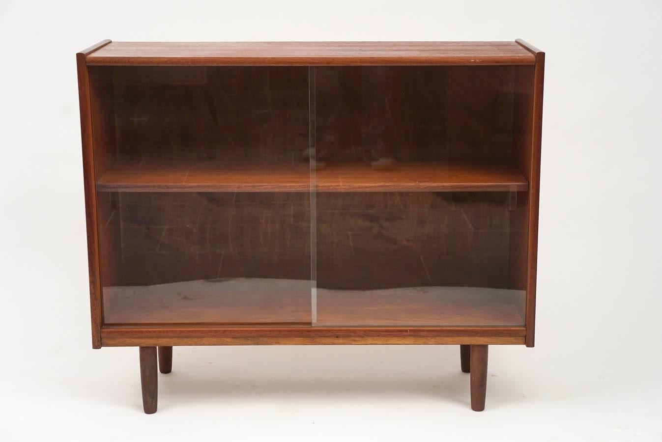 Nice small-scale Danish teak bookcase with sliding glass doors. The interior has one fixed shelf. 9 1/2