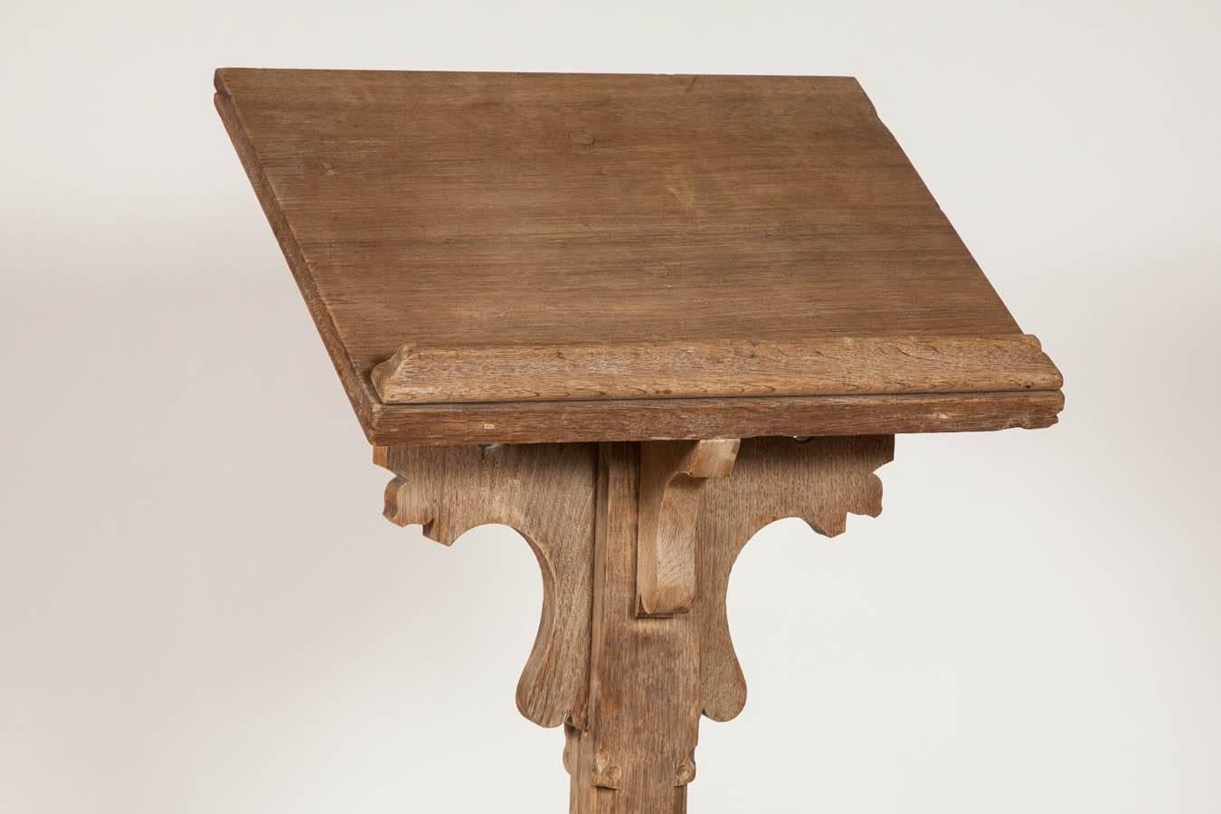 A tall antique lectern in solid oak. This original late 19th century lectern is in a Gothic Revival design with quatrefoil motifs carved on the supports.
