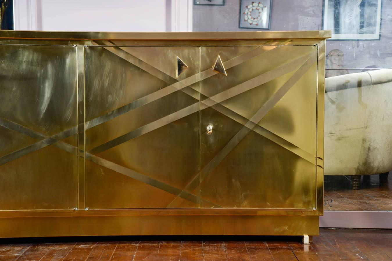 Sideboard in brass with four decorated doors.
