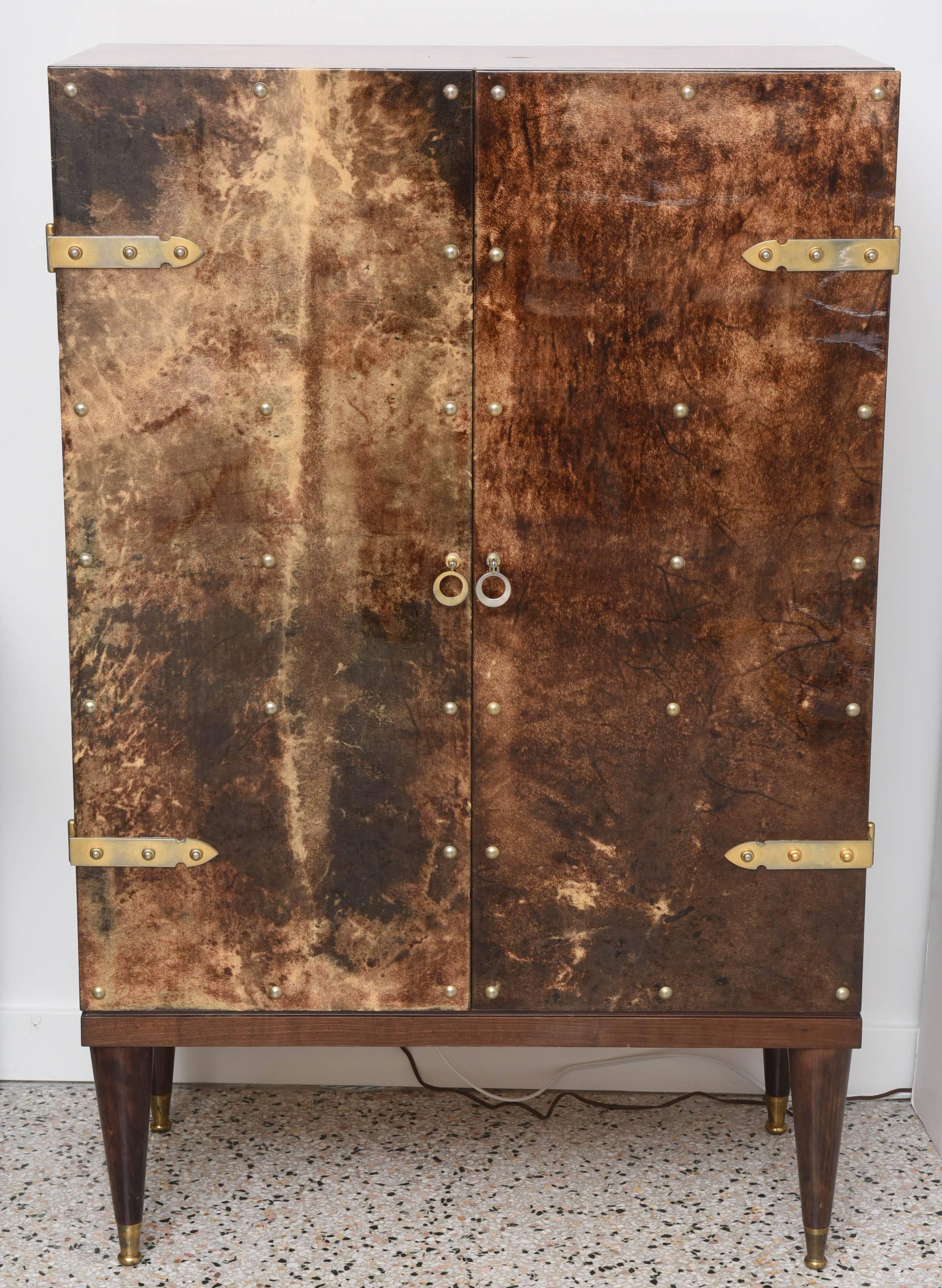 With its slender mahogany and brass legs and pristine lacquered goatskin this is definitely the rarest form and quality of the dry-bar cabinets designed and produced by the iconic Italian furniture designer Aldo Tura. 
 
This two door cabinet