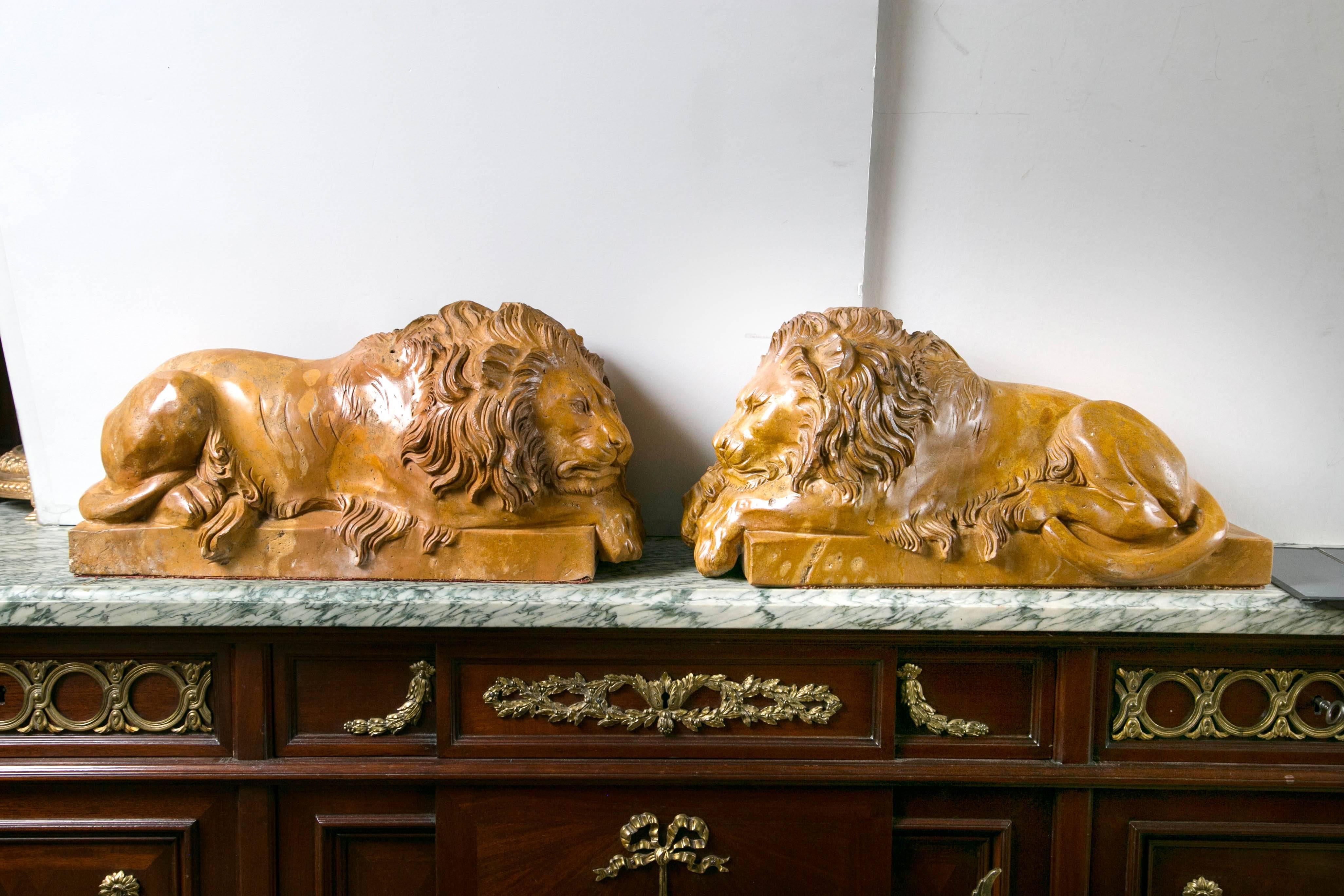 Hand-carved of Siena marble, a matched pair of sleeping lions on integral bases.