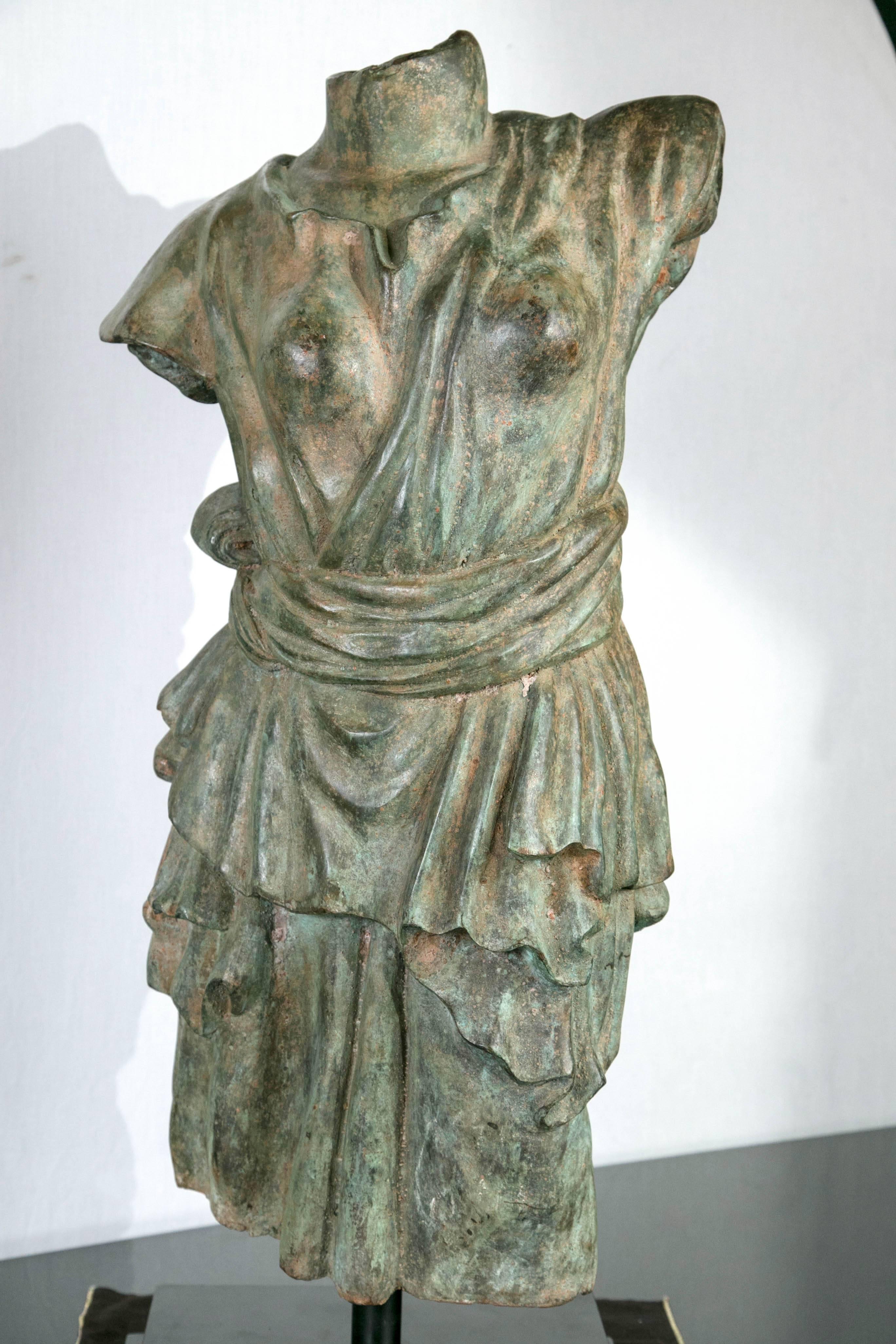 Set upon a two stepped black base. The bronze having a green/brown patina. The torso wearing a sashed at the waist garment.

Measurements refer to the base.