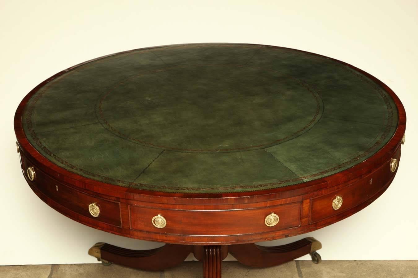 Regency mahogany round drum table with tooled leather top, reeded legs and brass caster feet.