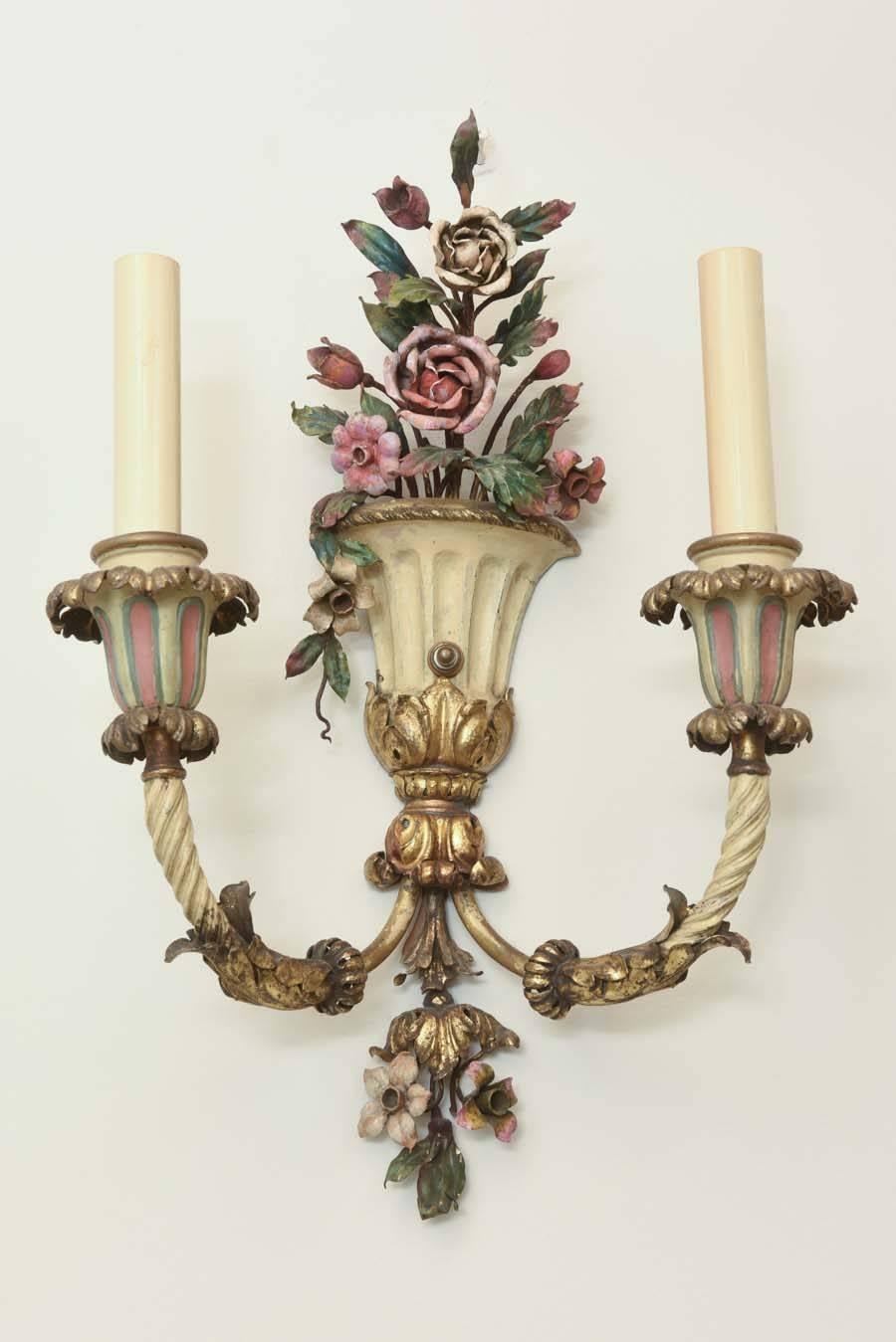 Fine pair of sconces, polychromed decoration over repousse bronze dore, each backplate shaped as a flower-filled urn, having double-candle, C-scroll arms, with acanthus details.  

Stock ID: D8529