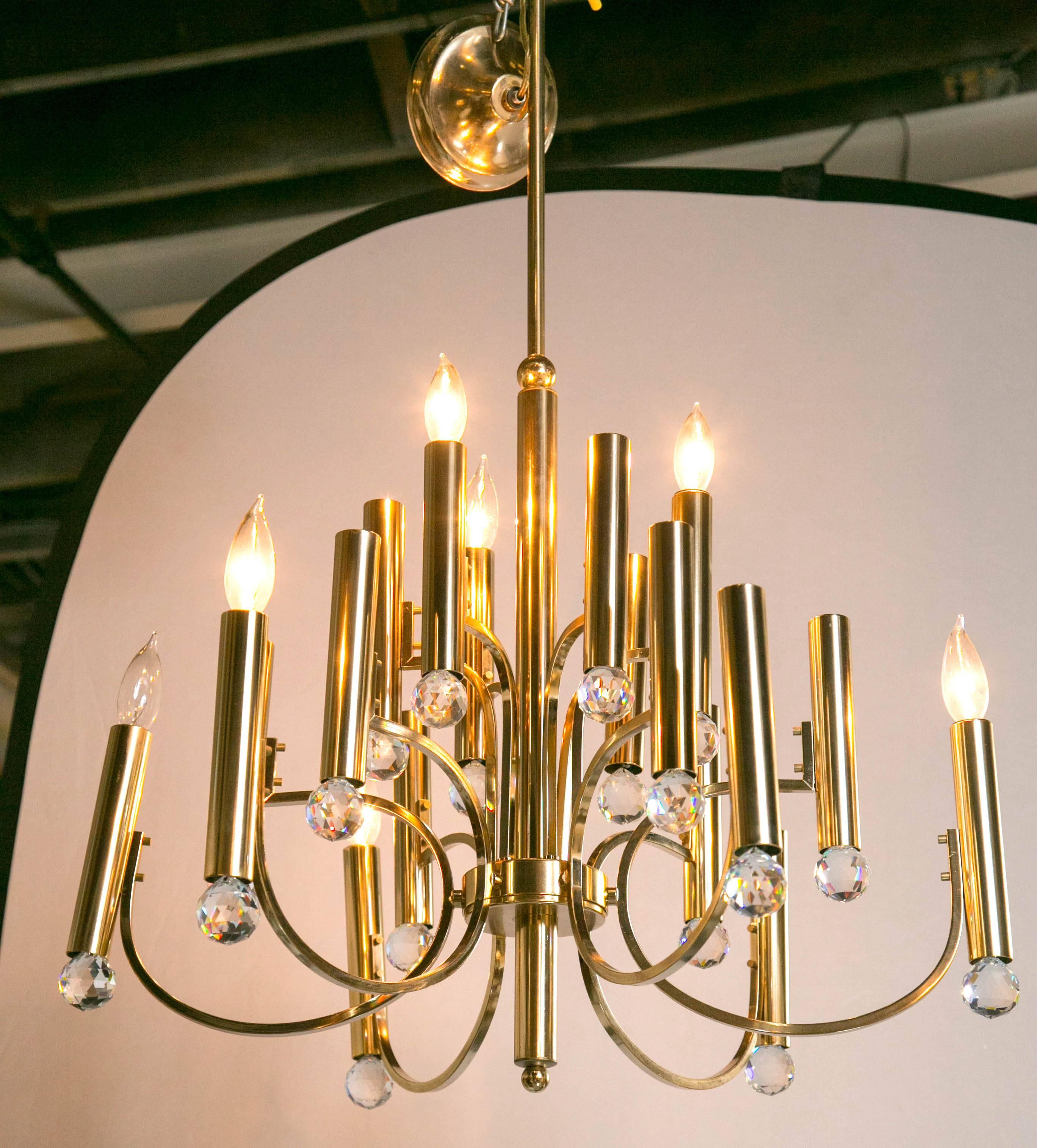 Parzinger Style Chandelier with Swarovski Crystal Prisms. This Tommi Parzinger inspired chandelier is solid brass having 18 lights supported by flowing elegant arms. A fine representation of the Hollywood Regency era. 