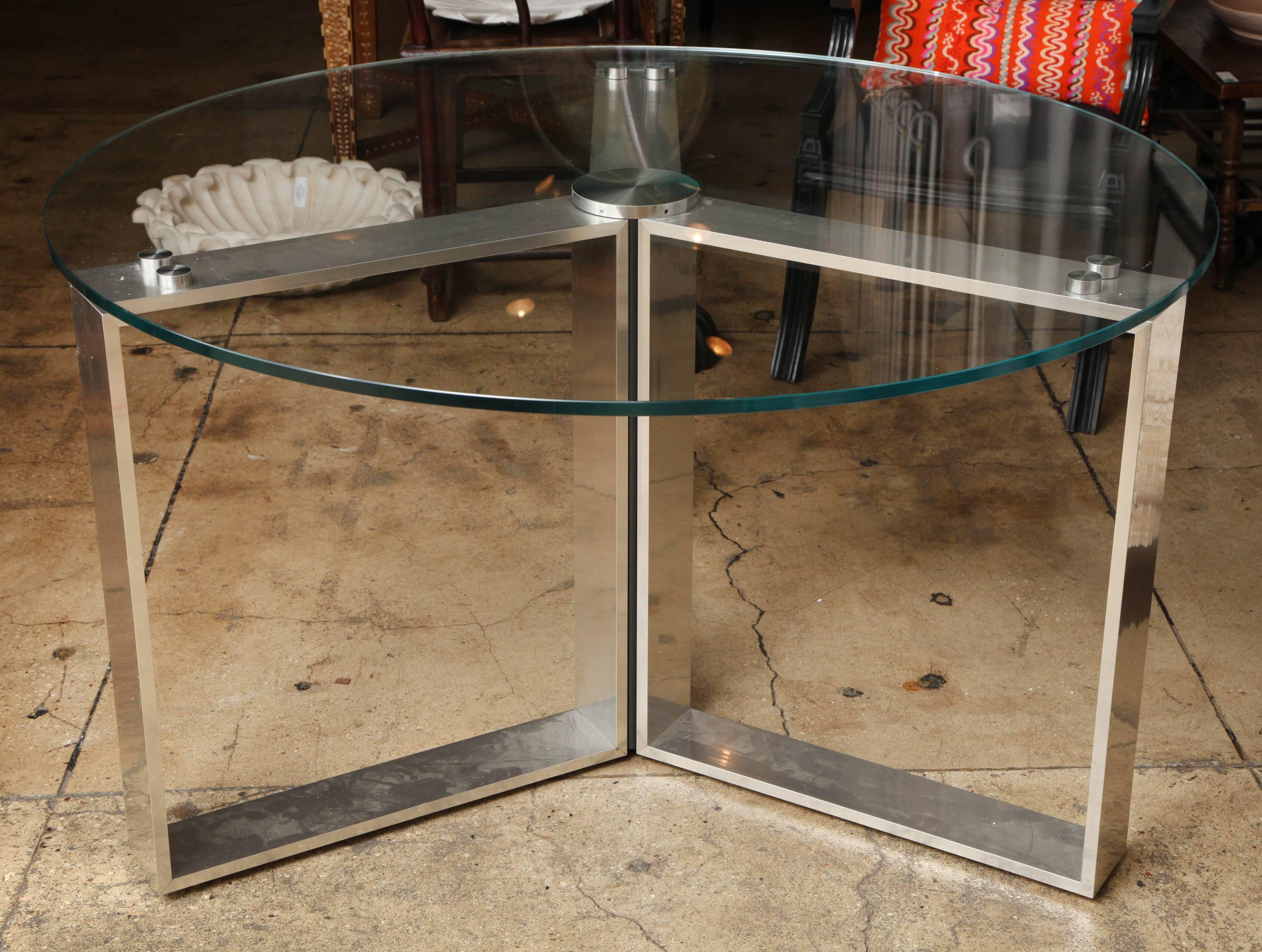 A round dining table with a clear glass top on a polished steel frame base, from France.