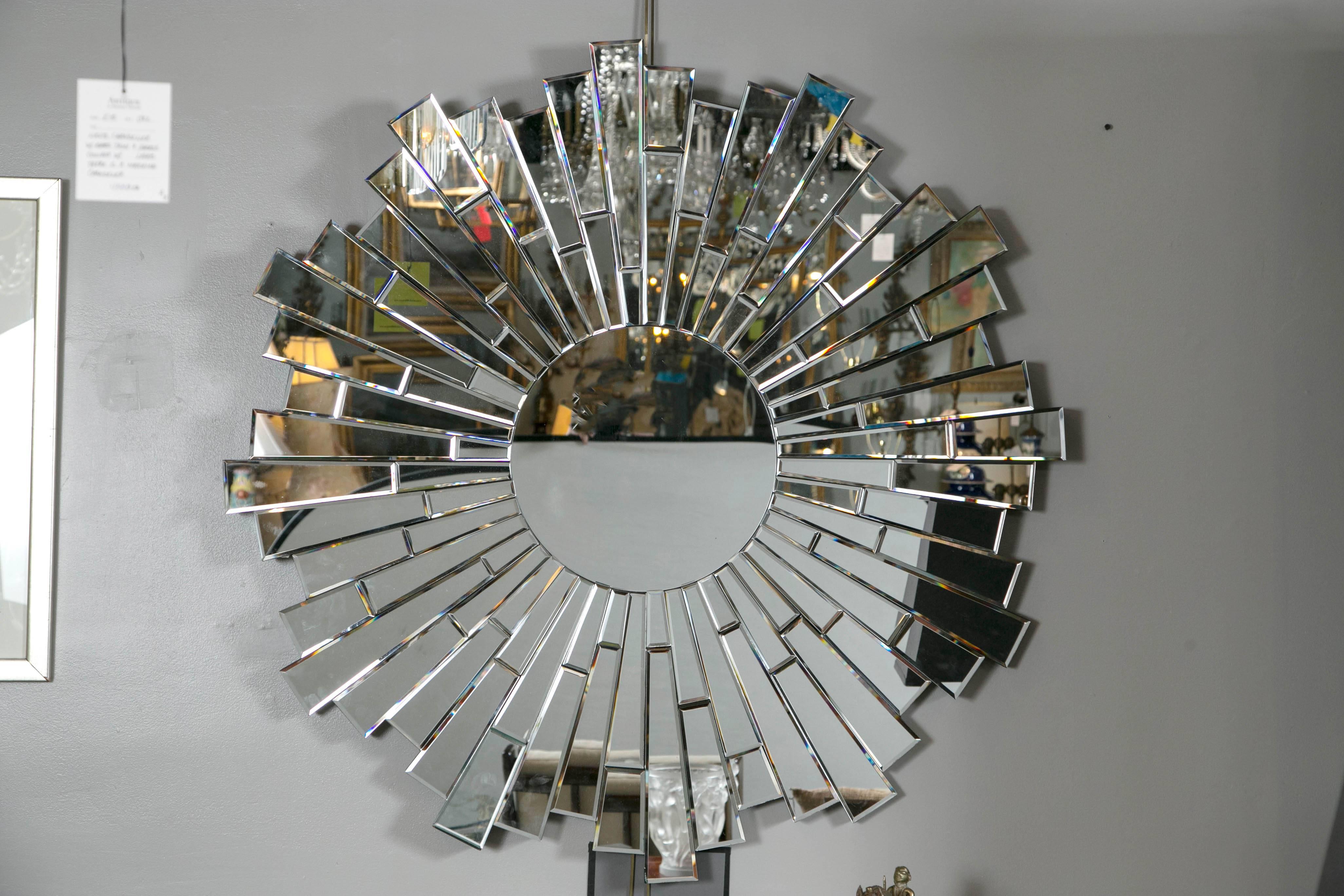 Large sunburst mirror comprised of individual pieces of beveled mirror that surround center mirror. All mirrors are mounted on wood.