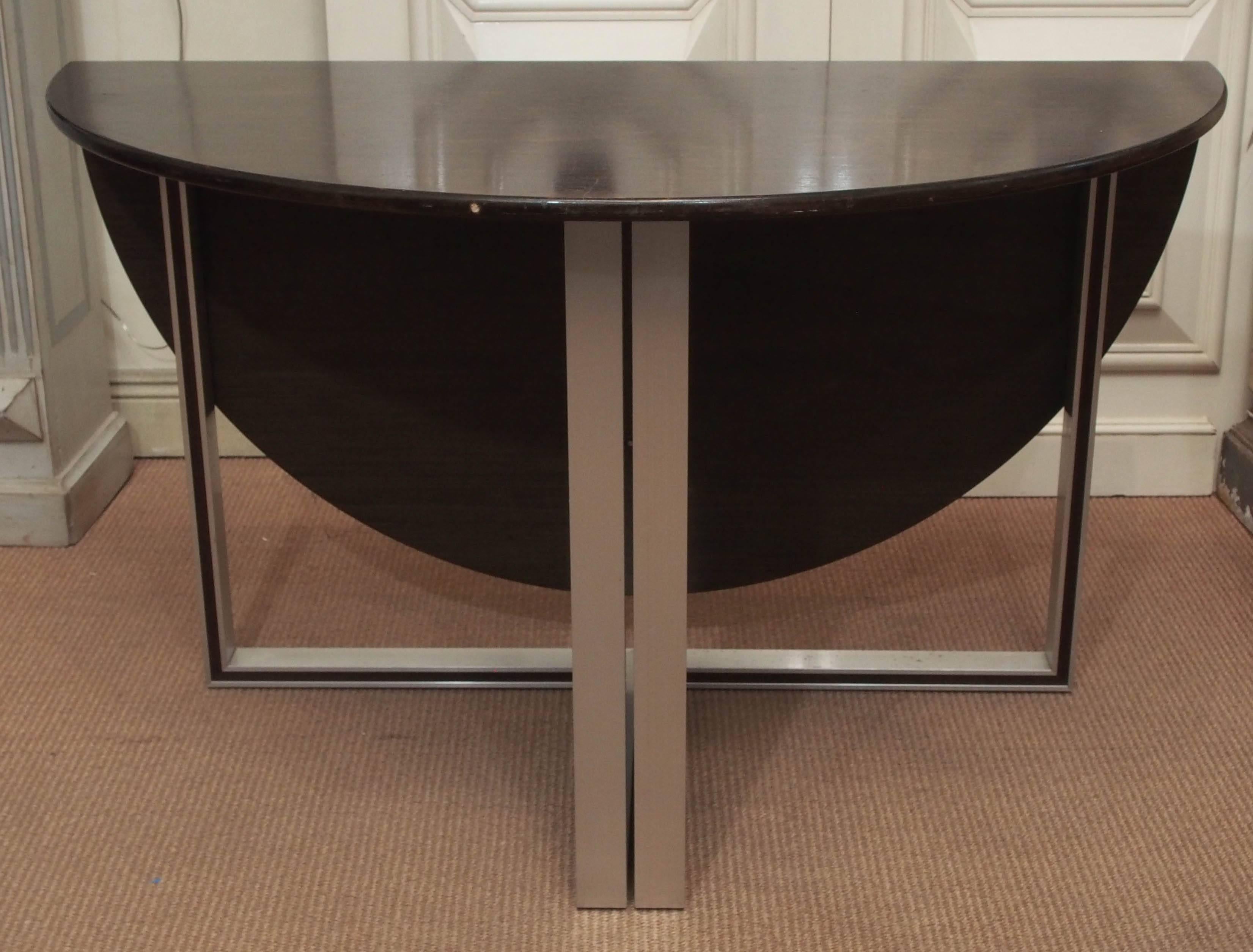A beautiful modern circular table with a folding leaf and metal legs. The table can be flush with a wall or set as a standalone piece. Its versatility would make it a great addition to any space.