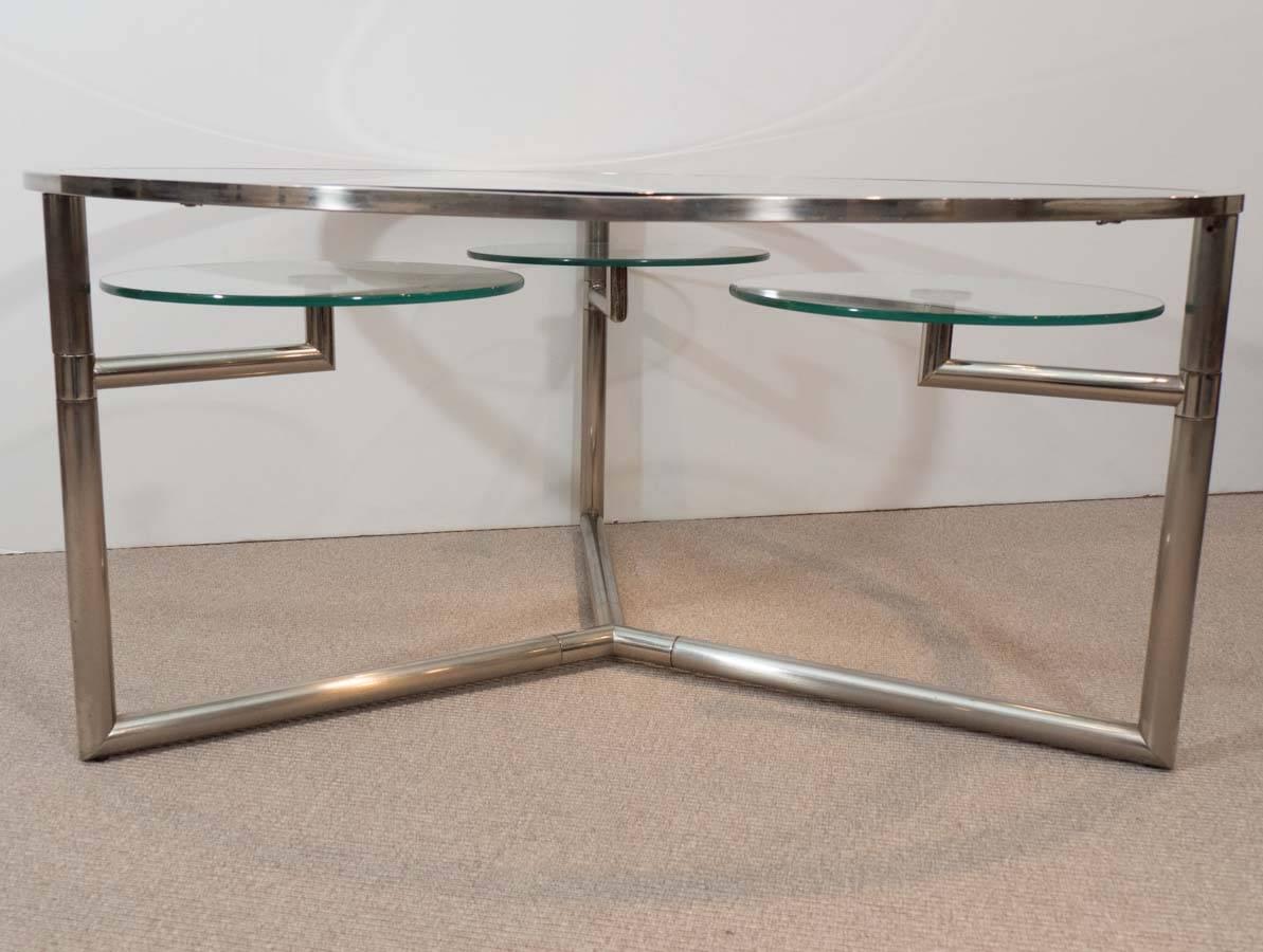 Round table with clear glass top with three undermounted glass swivels on chrome base.