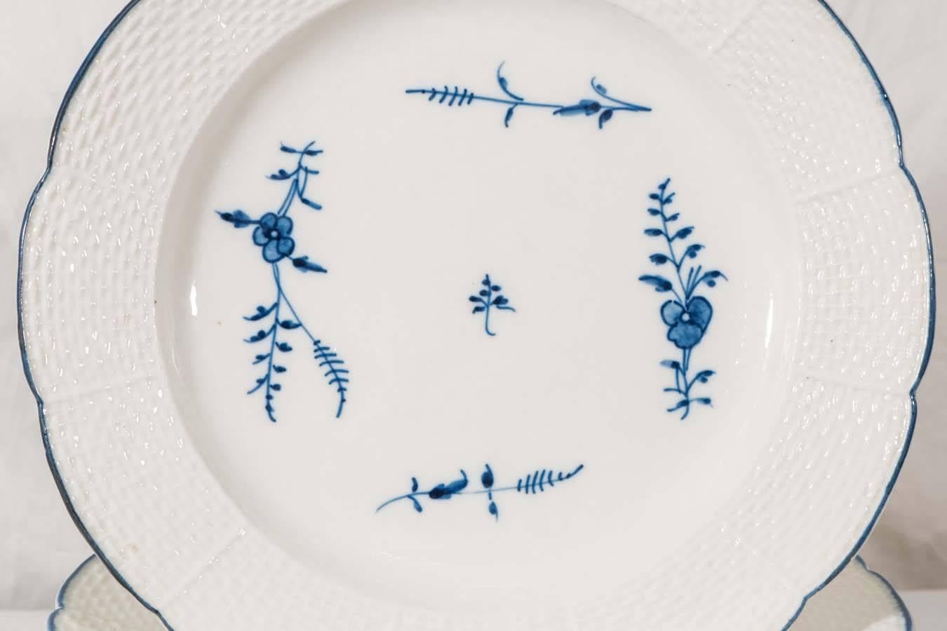 A set of 18th century Chantilly soft paste blue and White dinner plates painted with 'Chantilly Sprigs' and blue-line rims. They have a wide raised basket weave border. Each dish is marked on the reverse with the Chantilly hunting Horn mark in