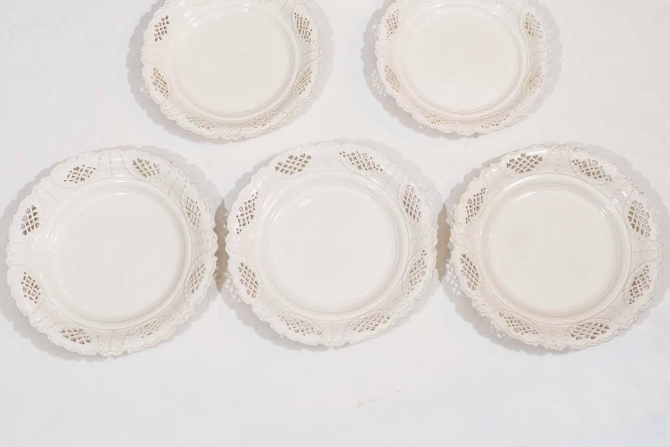 We have four dishes. A group of pierced creamware dishes made in England, circa 1800. The rim of each dish decorated with swags and eight pierced panels. The reticulated decoration includes hearts and diamonds. The borders have raised, lobed edges.