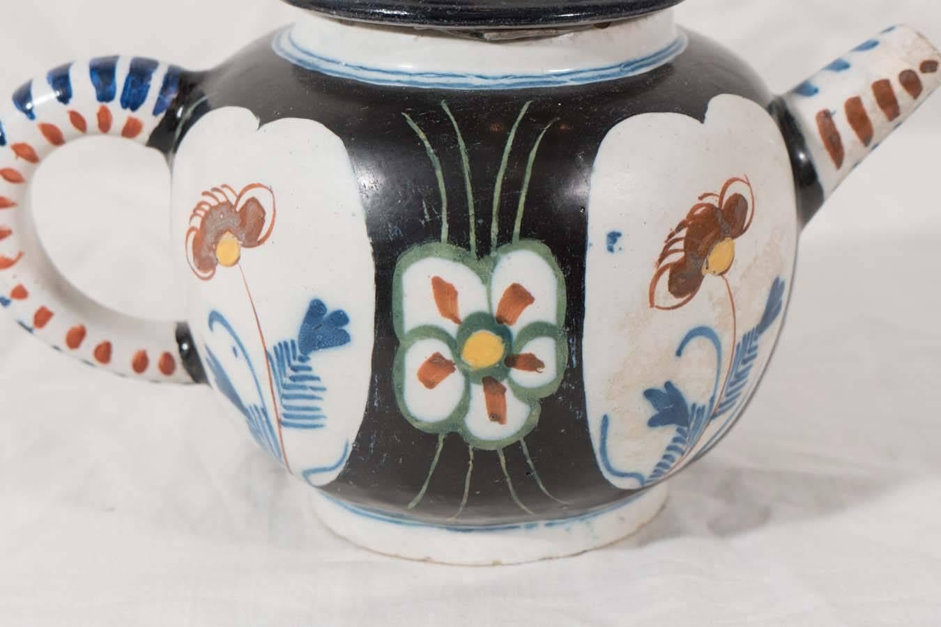 A small decorative Dutch Delft teapot with rare black tin-glaze and painted polychrome floral decoration, the handle and spout decorated with dashes. The teapot in a traditional Chinese form. The spout shortened in the Dutch fashion.
 The