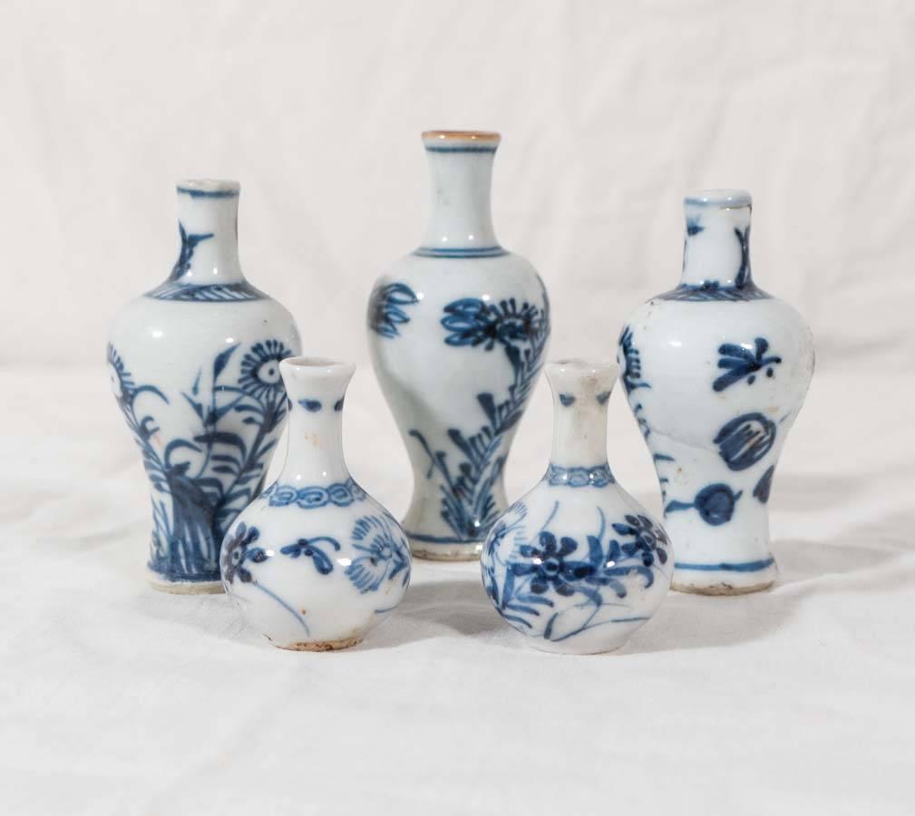 A Kangxi miniature blue and white five-piece garniture comprising three baluster vases and a pair of gourd shaped vases. The garniture is decorated with simple flower sprigs painted in tones of cobalt blue.