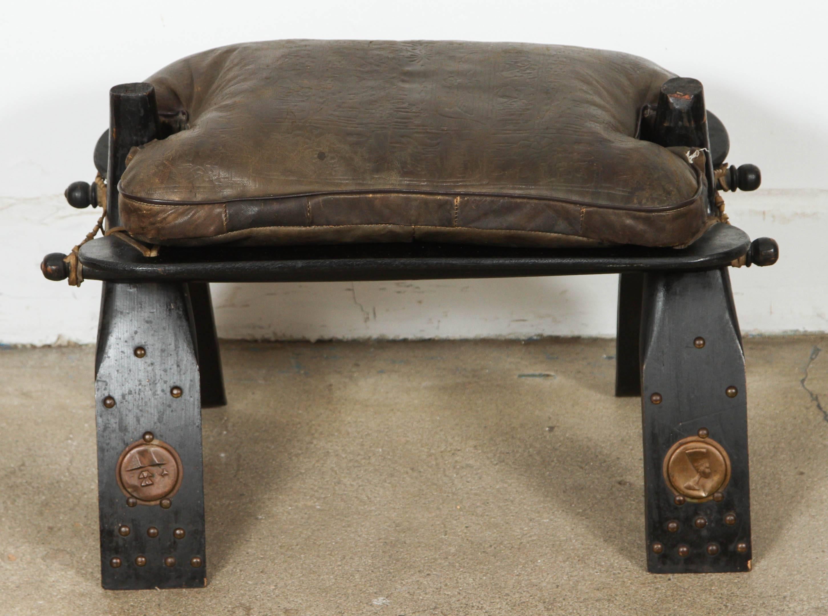 Traditionally used to ride camels in the desert, this camel saddle could be used as a foot stool or just as an accent piece in any room.
All hand-carved ebonized wood and adorned with brass nails and decoration with a black faux leather cushion.
 